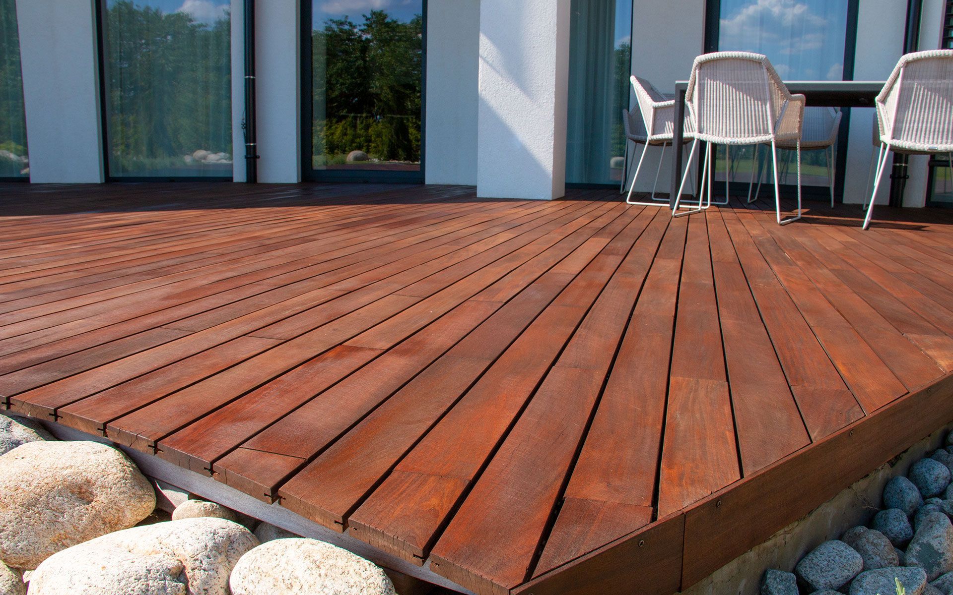 A wooden deck with a metal railing and trees in the background.