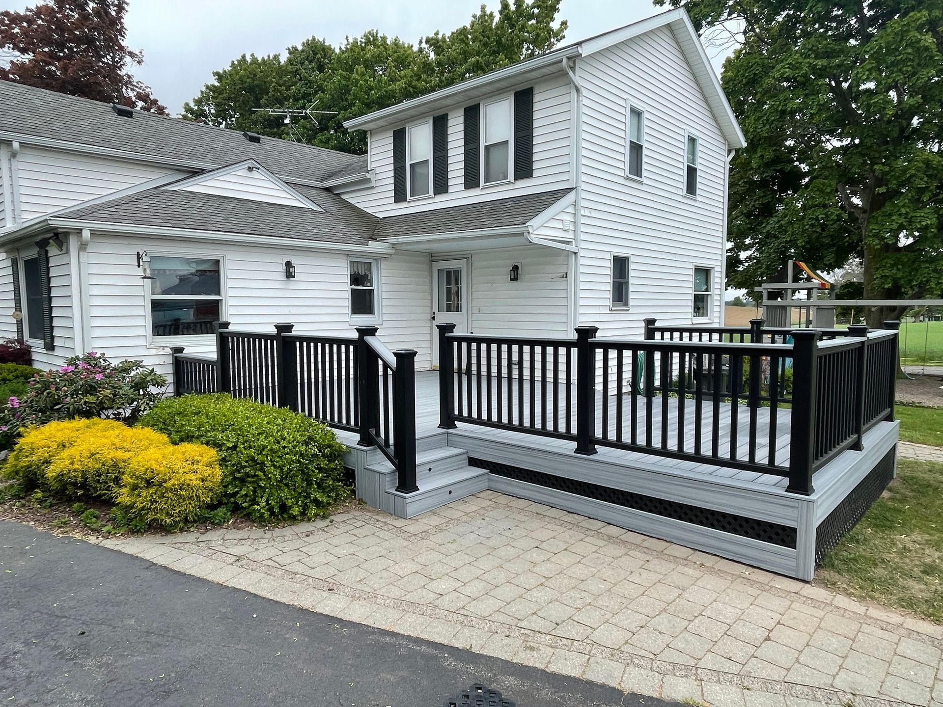 A white house with a black deck in front of it.
