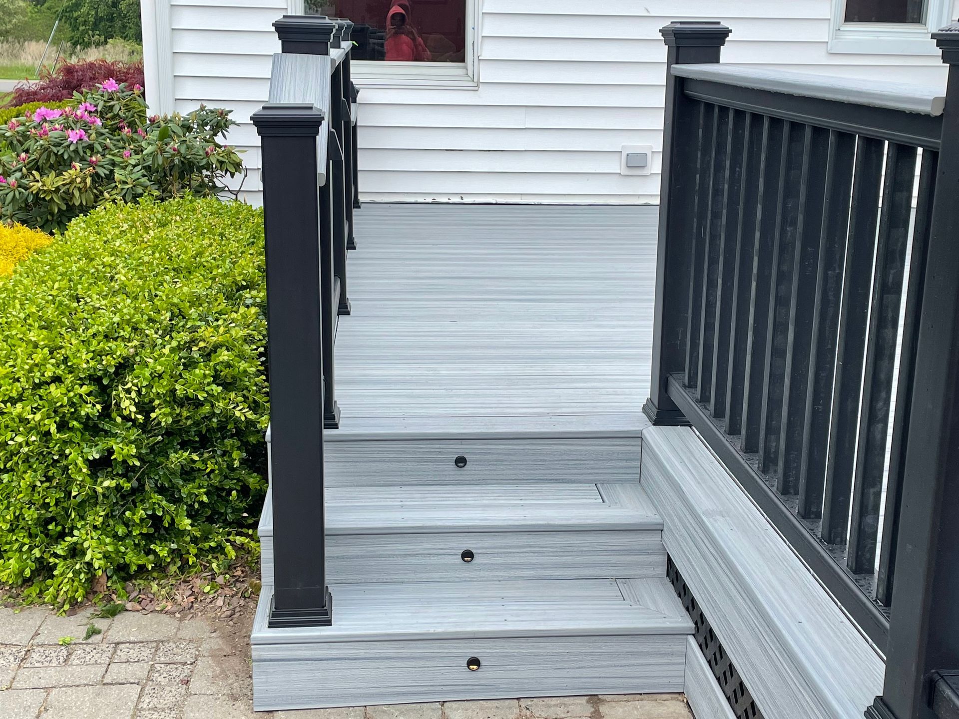 A white house with a gray deck and black railing.