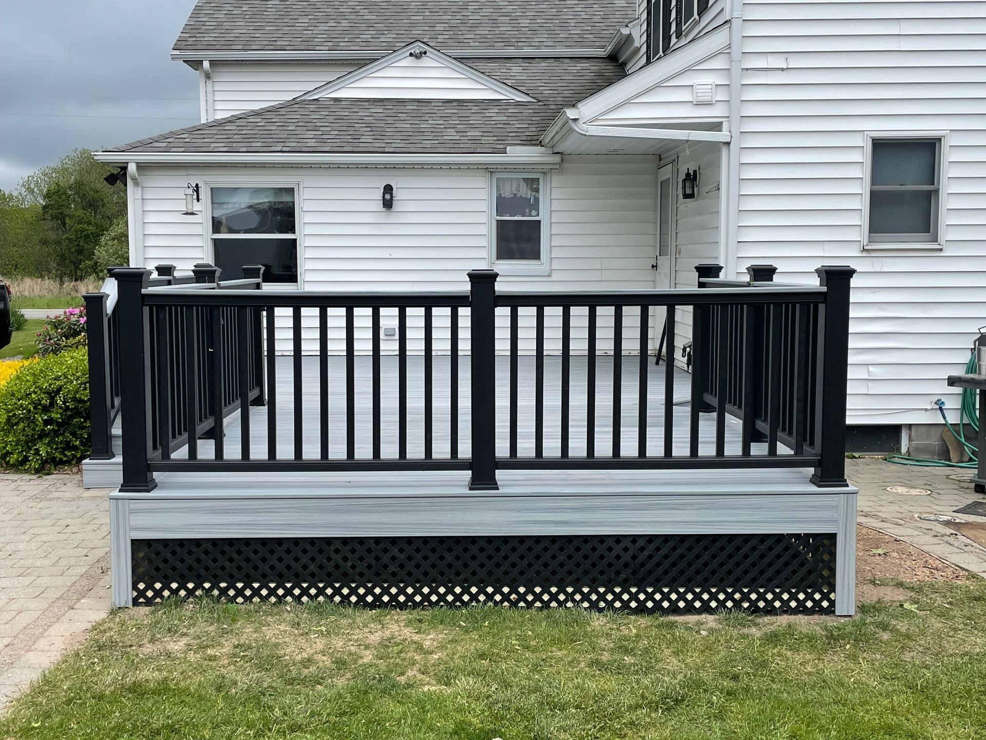 A white house with a black deck in front of it.