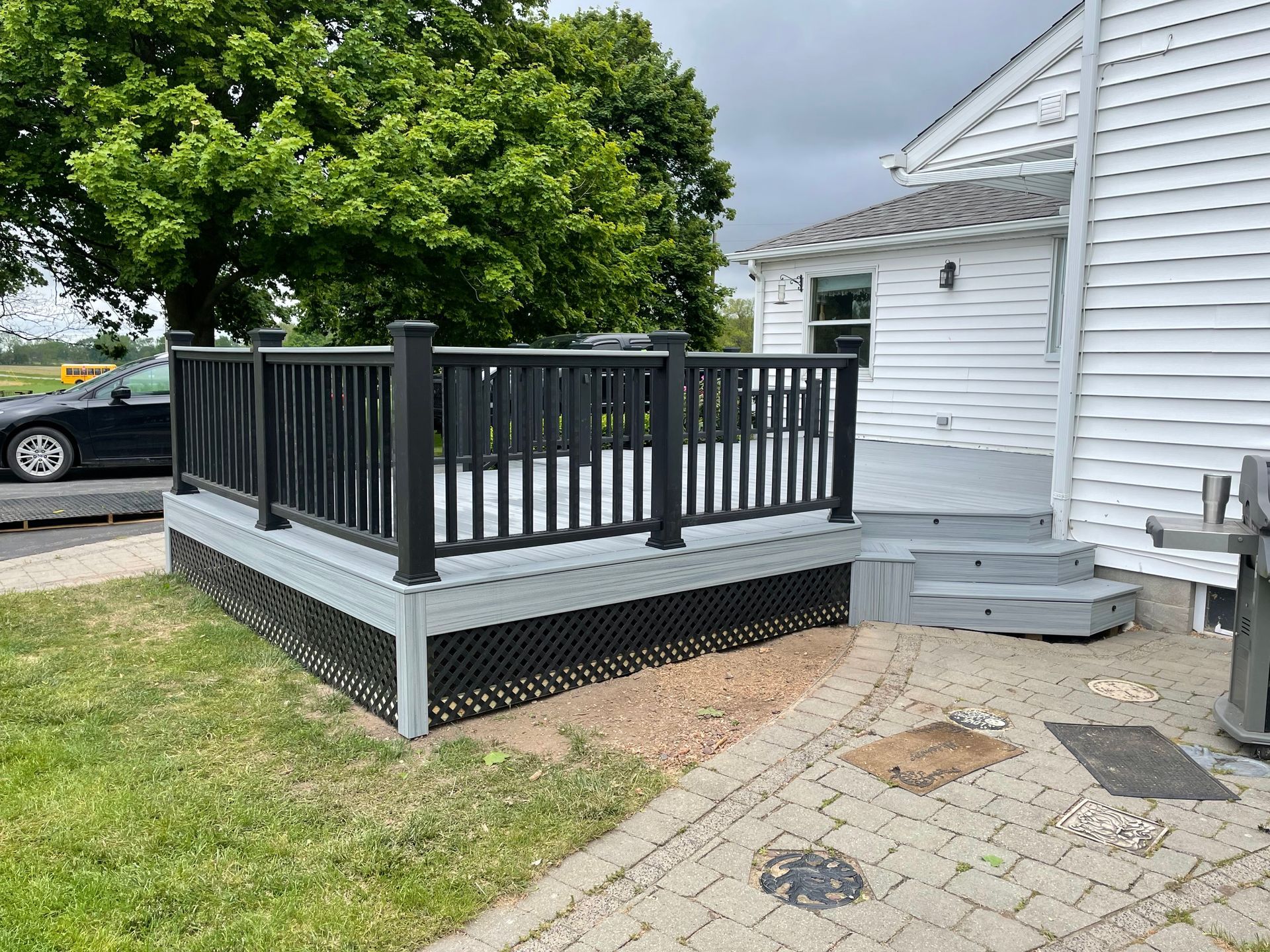 A white house with a black deck and stairs in front of it.