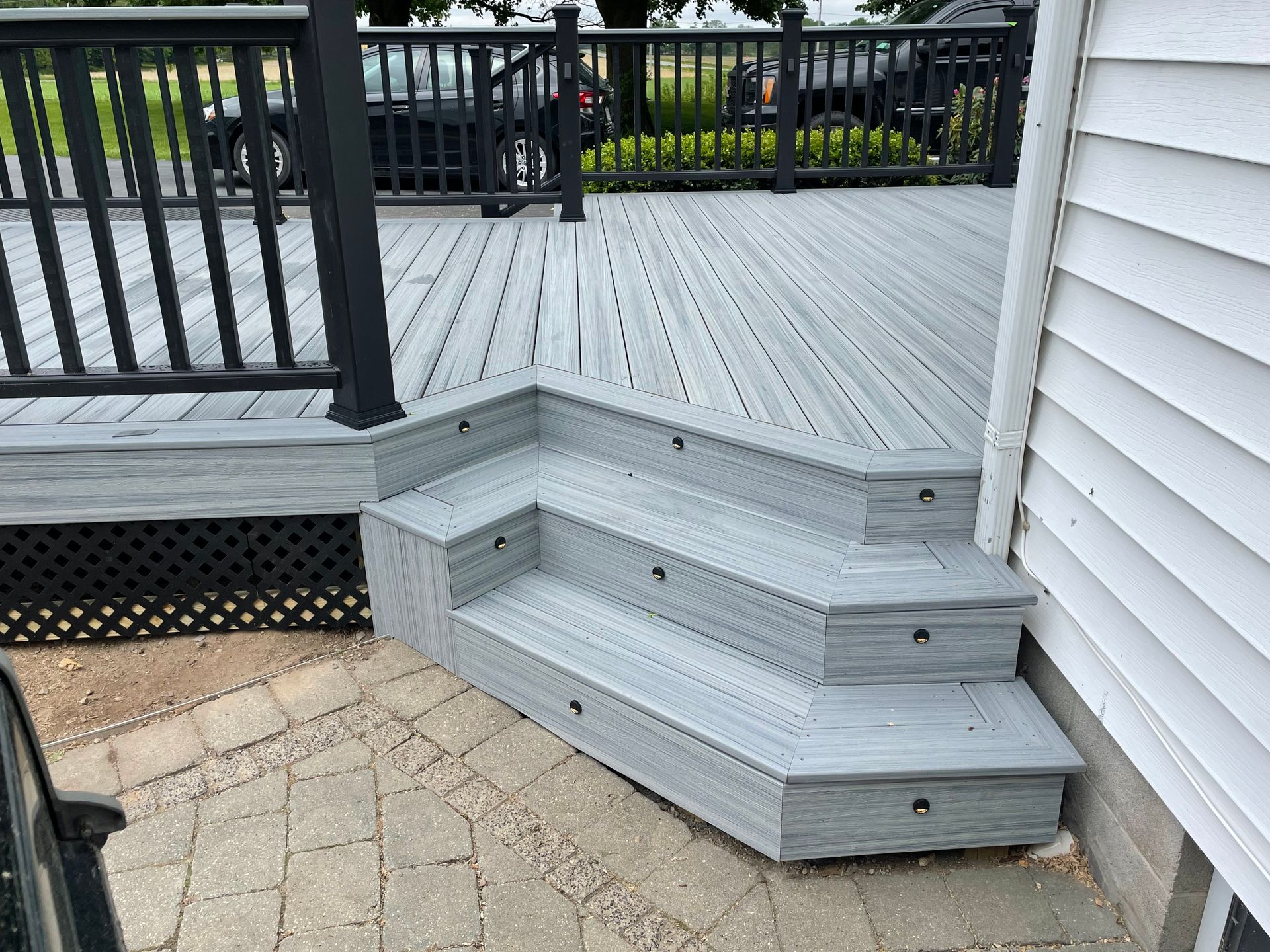 A deck with stairs leading up to it and a black railing.