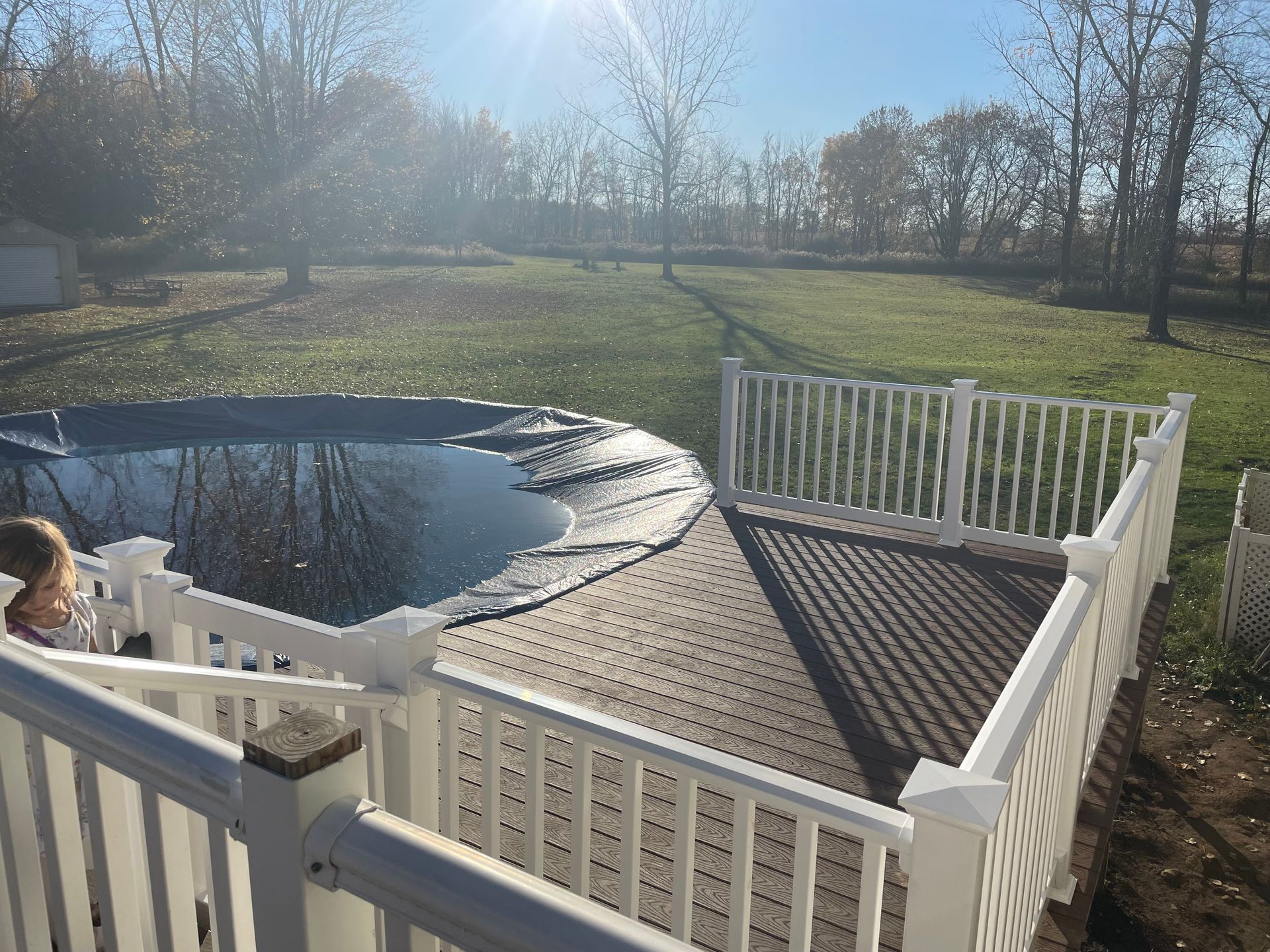 A person is standing on a deck next to a pool.
