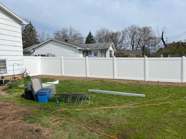 There is a white fence in the backyard of a house.