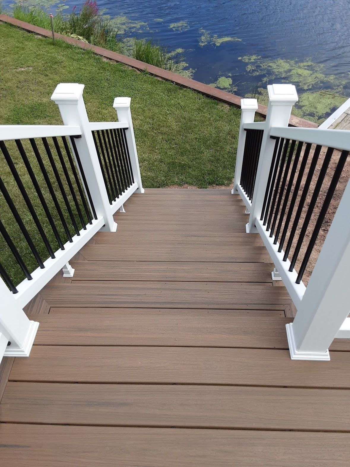 A wooden deck with stairs leading up to a lake.