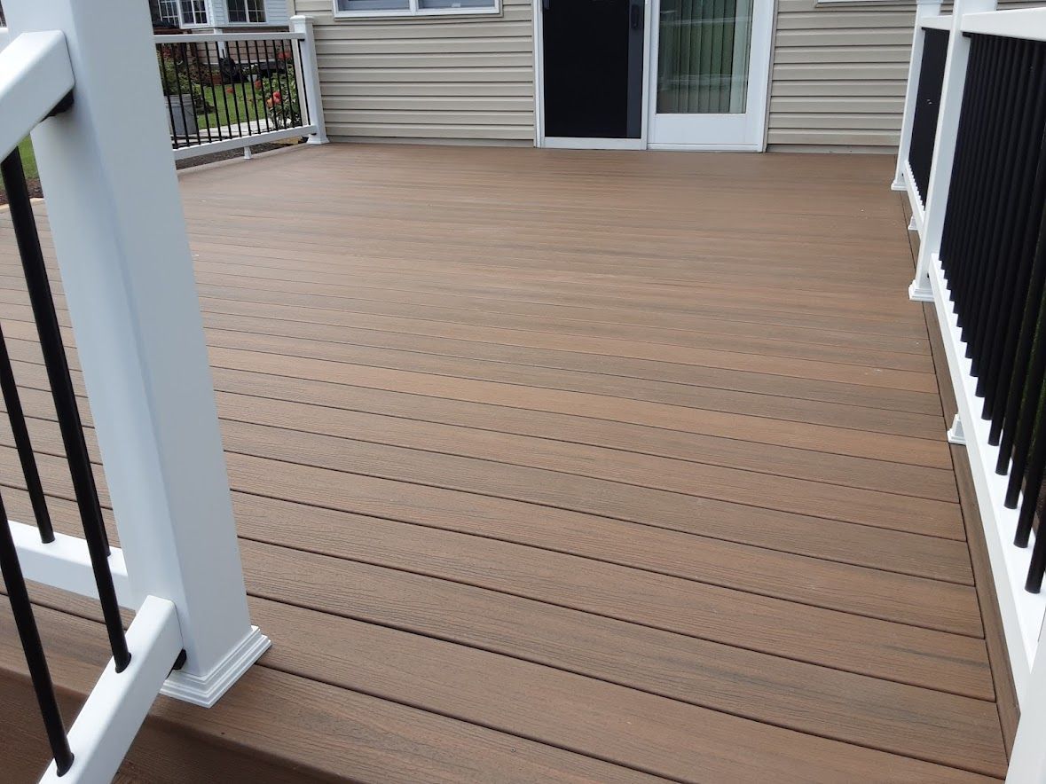 A wooden deck with a white railing and a sliding glass door