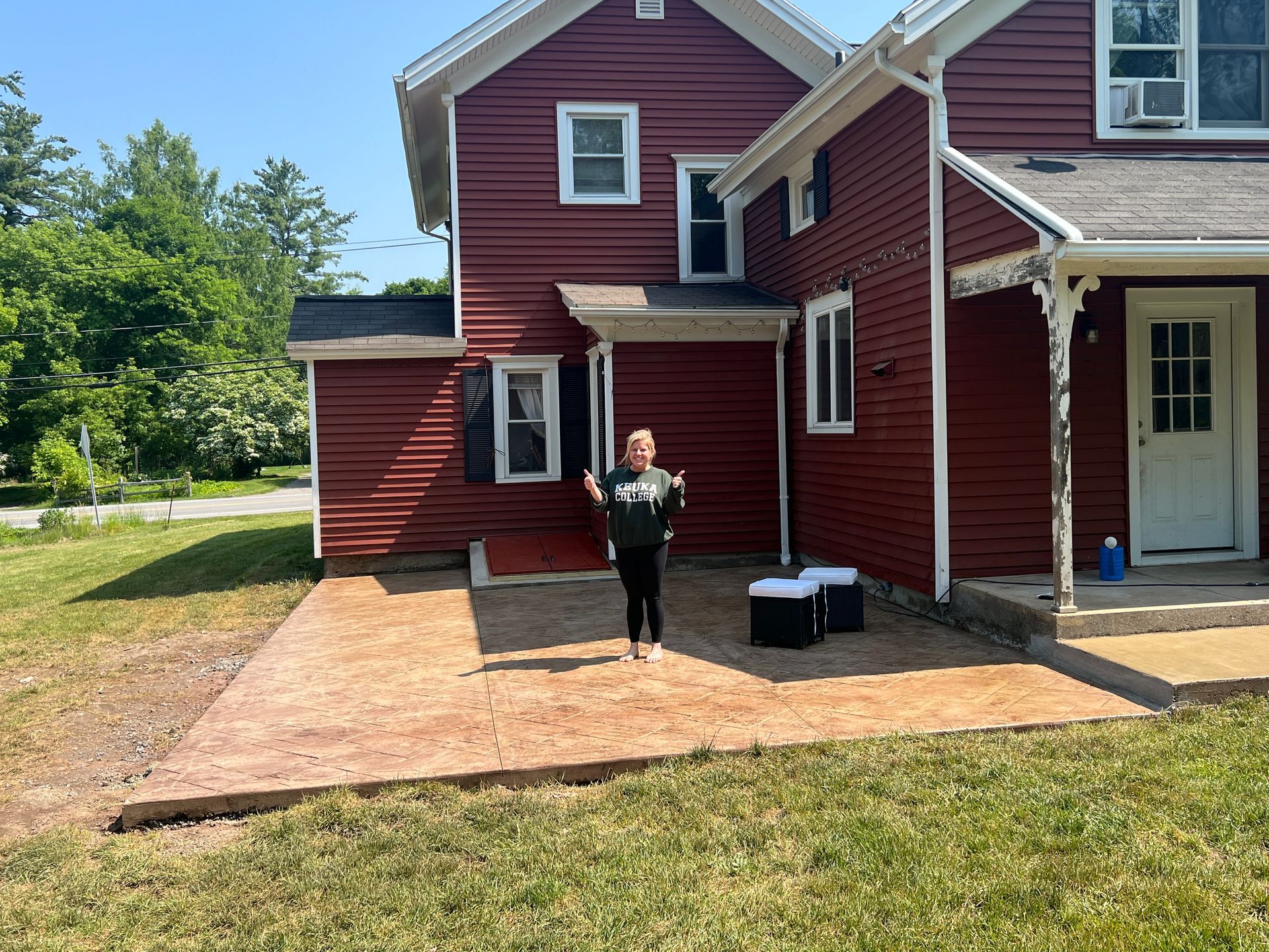 A woman is standing in front of a red house.