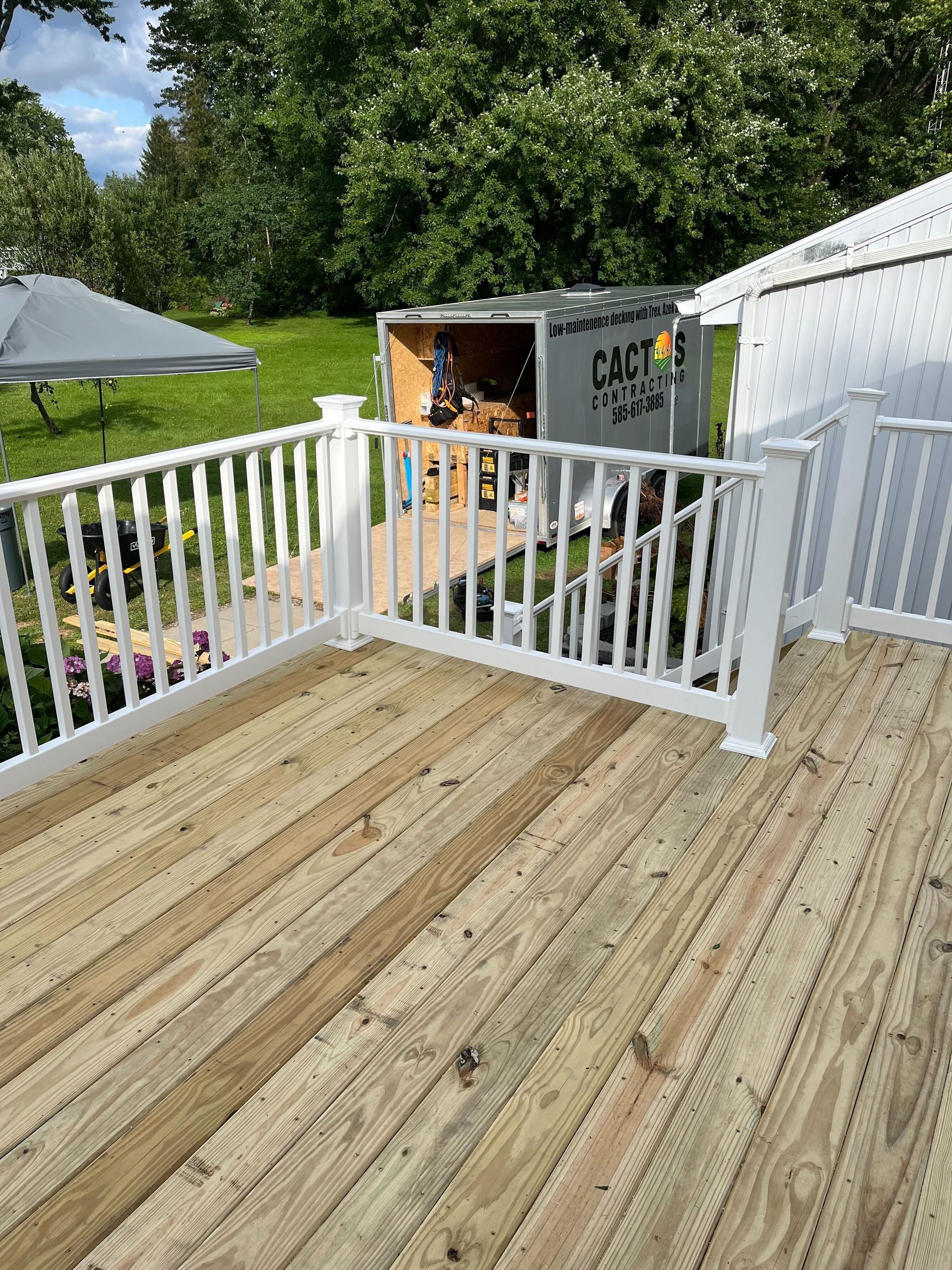 A wooden deck with a white railing and a trailer in the background.