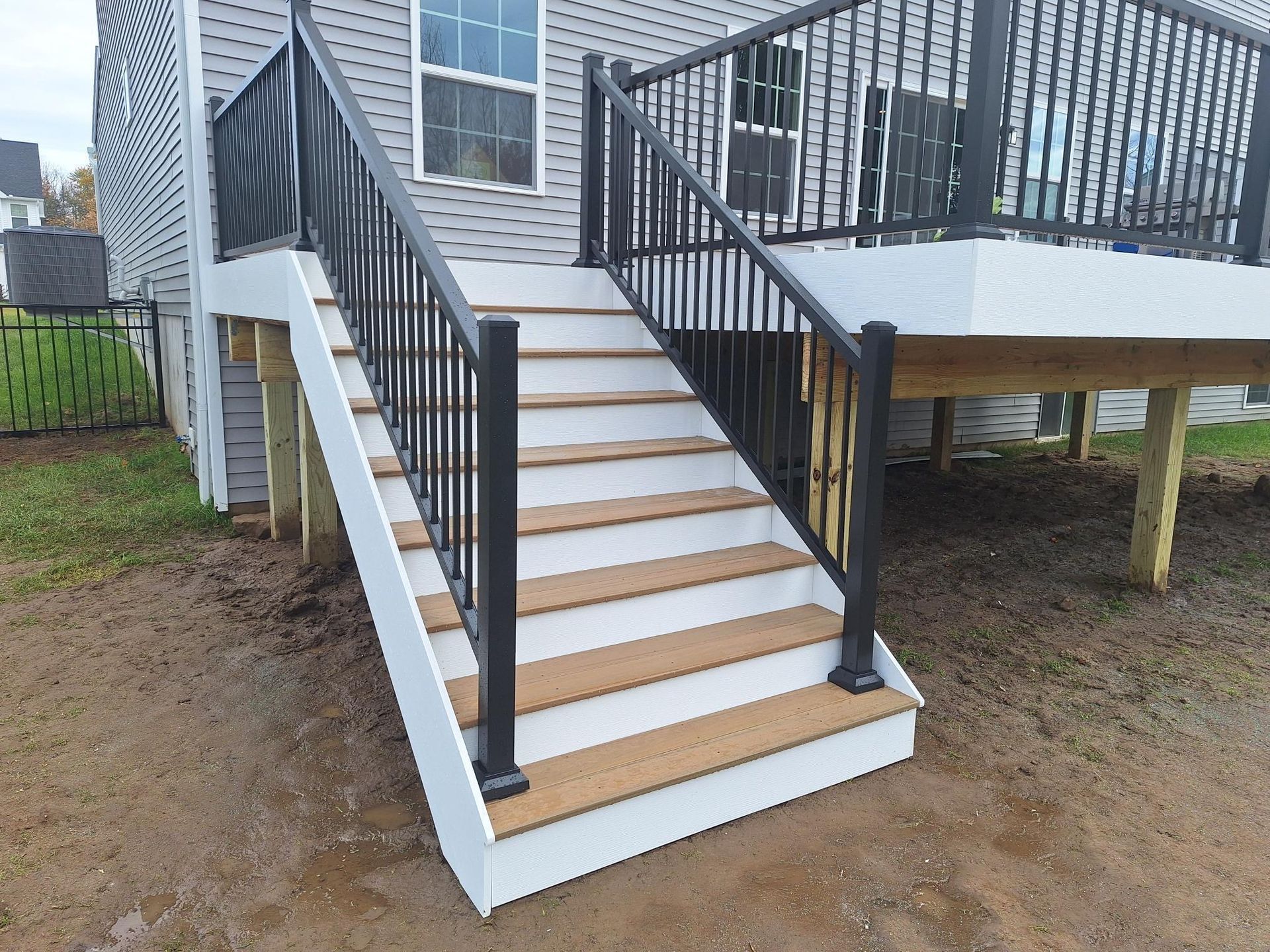 A deck with stairs leading up to it and a black railing.
