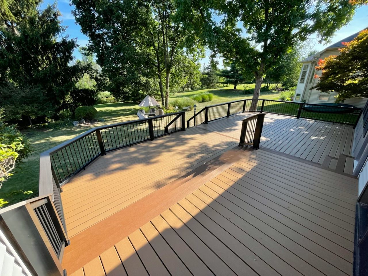 A wooden deck with a metal railing and stairs leading up to it.