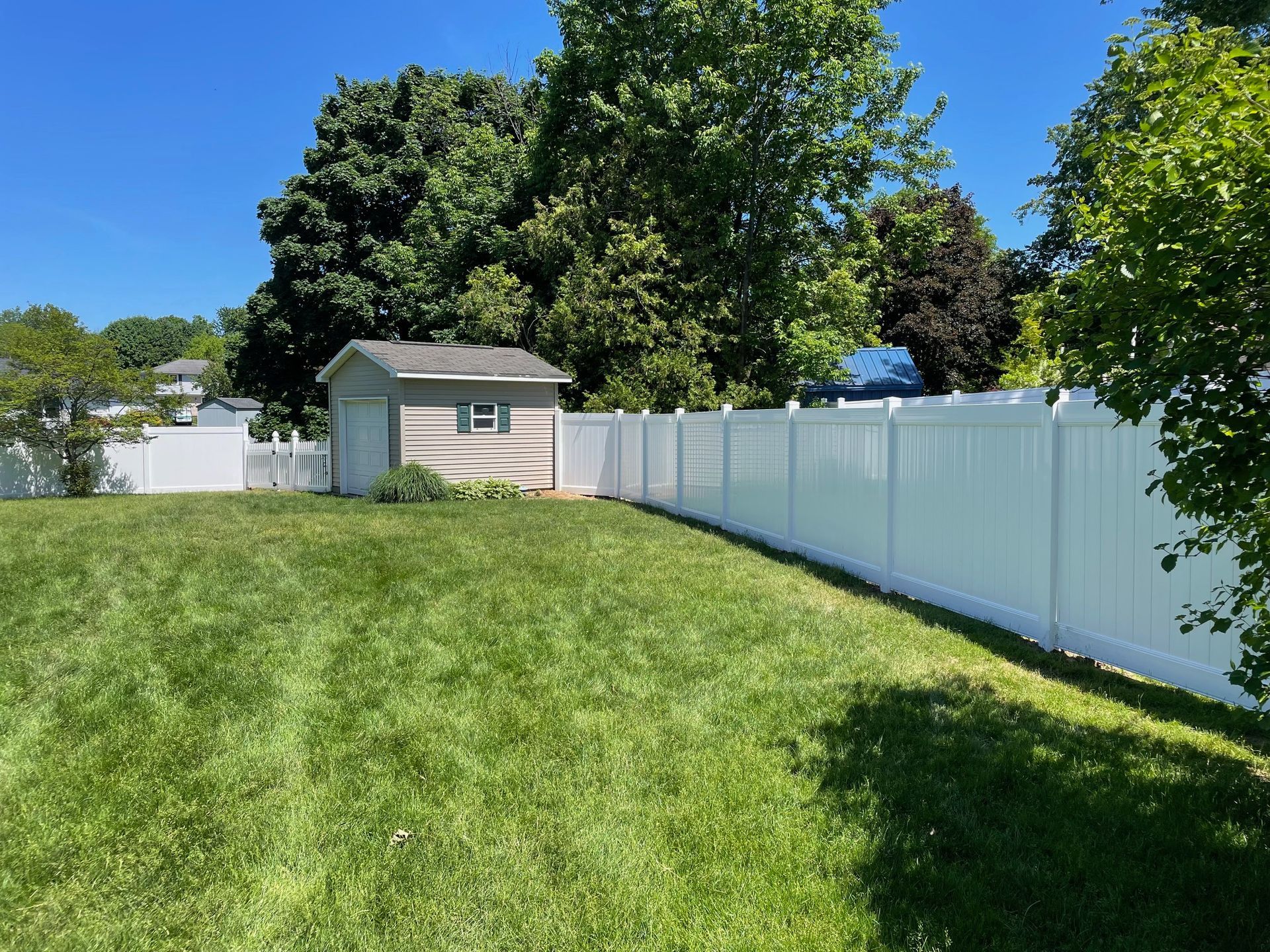 A backyard with a white fence and a shed.