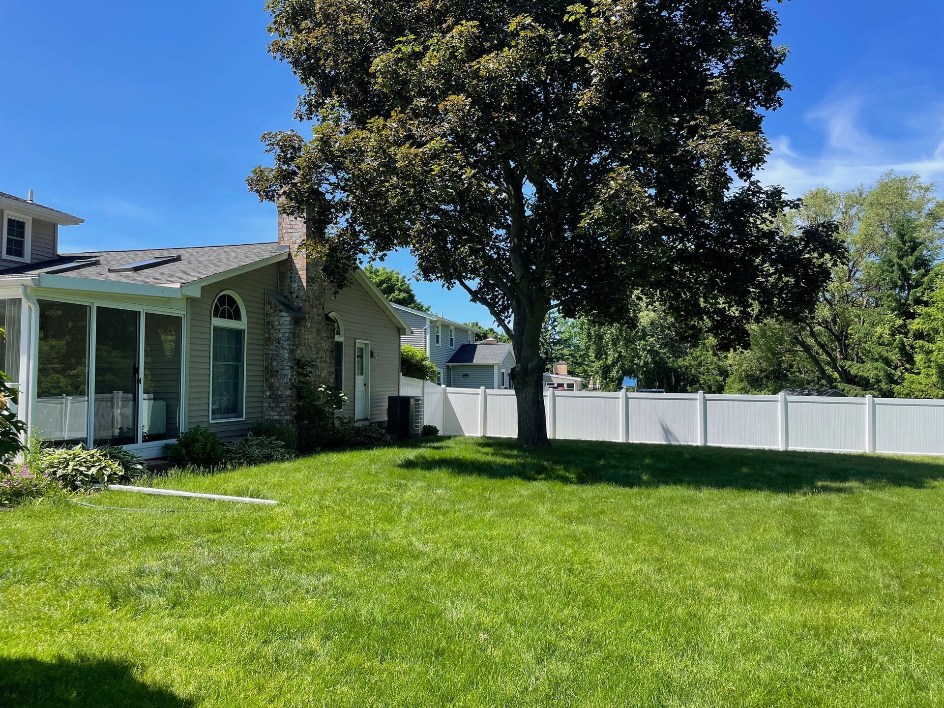 A house with a white fence and a tree in the backyard.