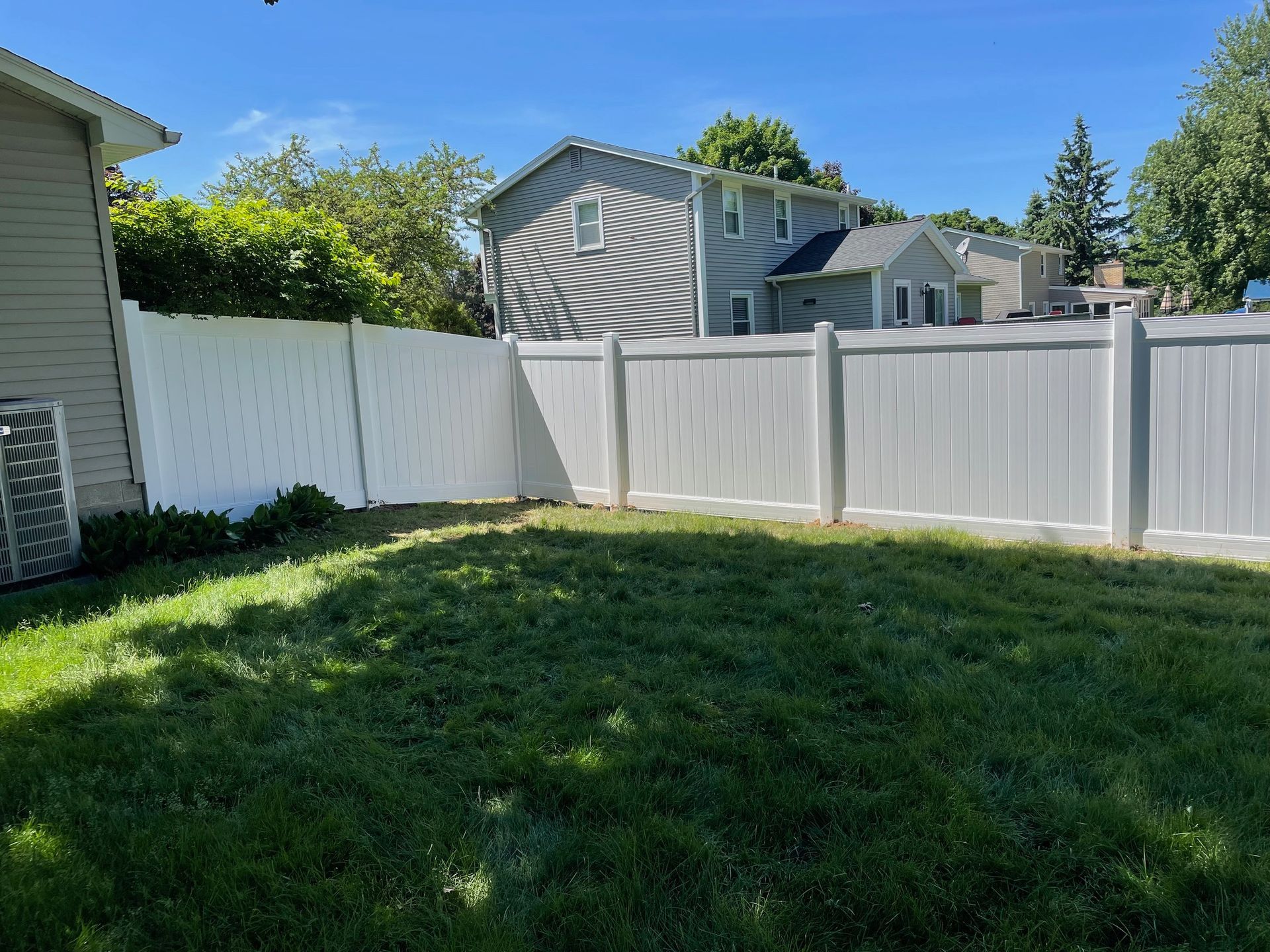 There is a white fence in the backyard of a house.