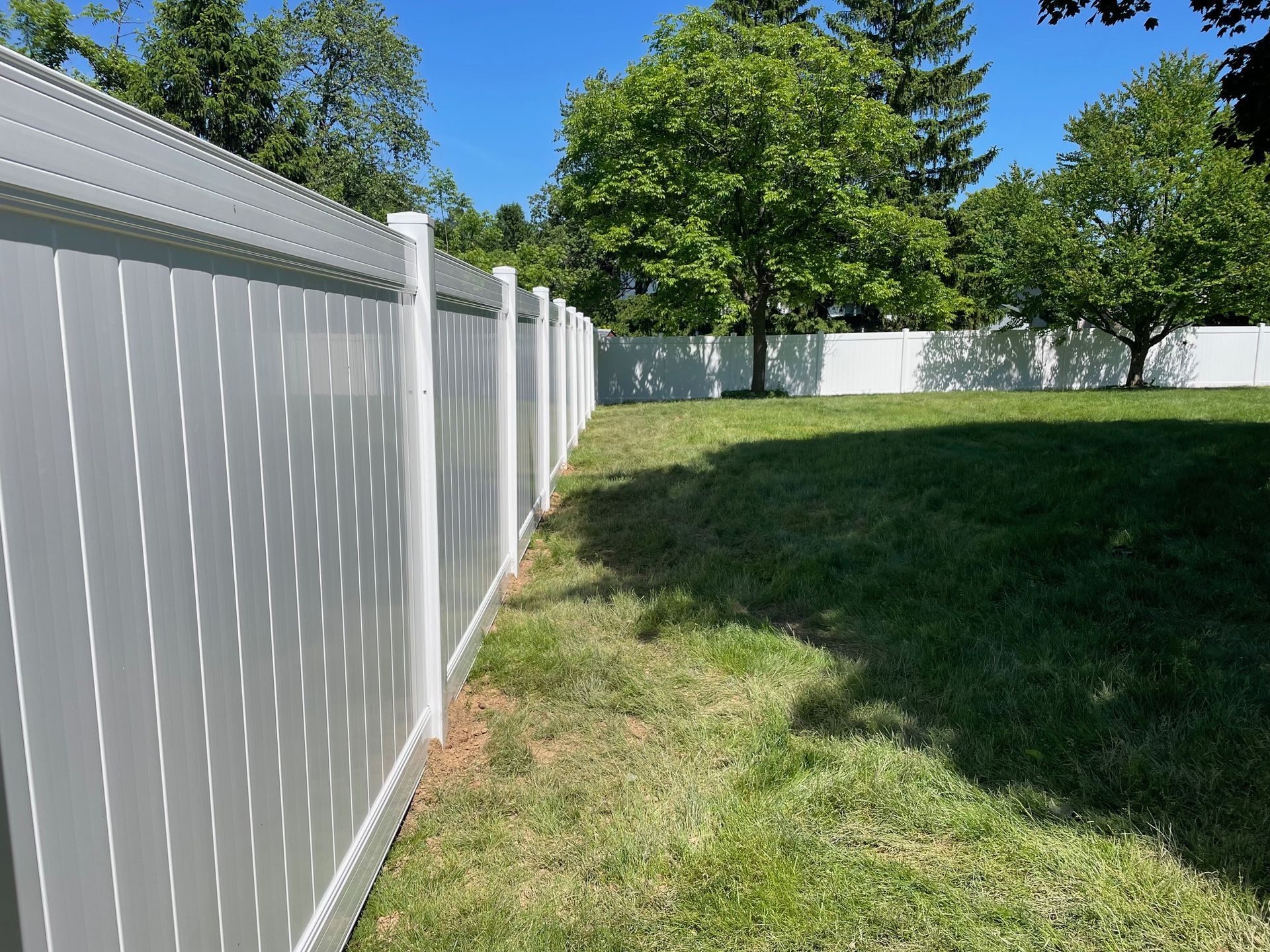 A white fence surrounds a lush green yard.