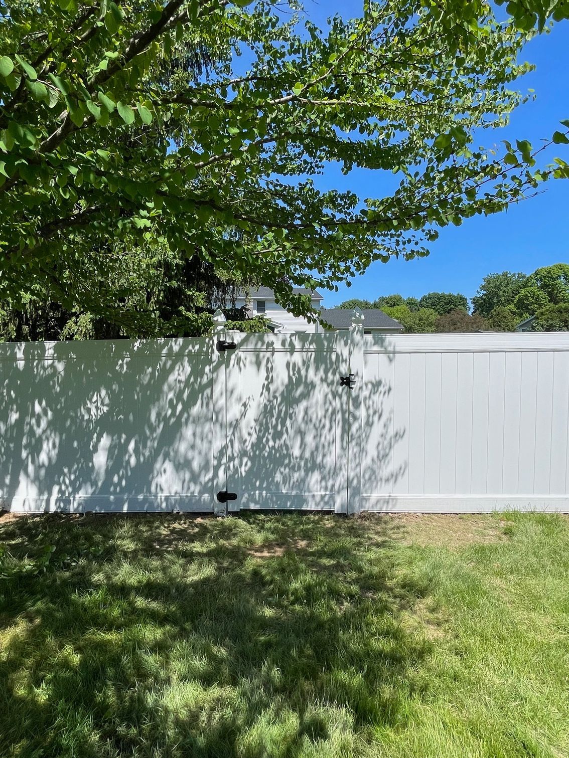 A white fence in a backyard with a tree in the background.