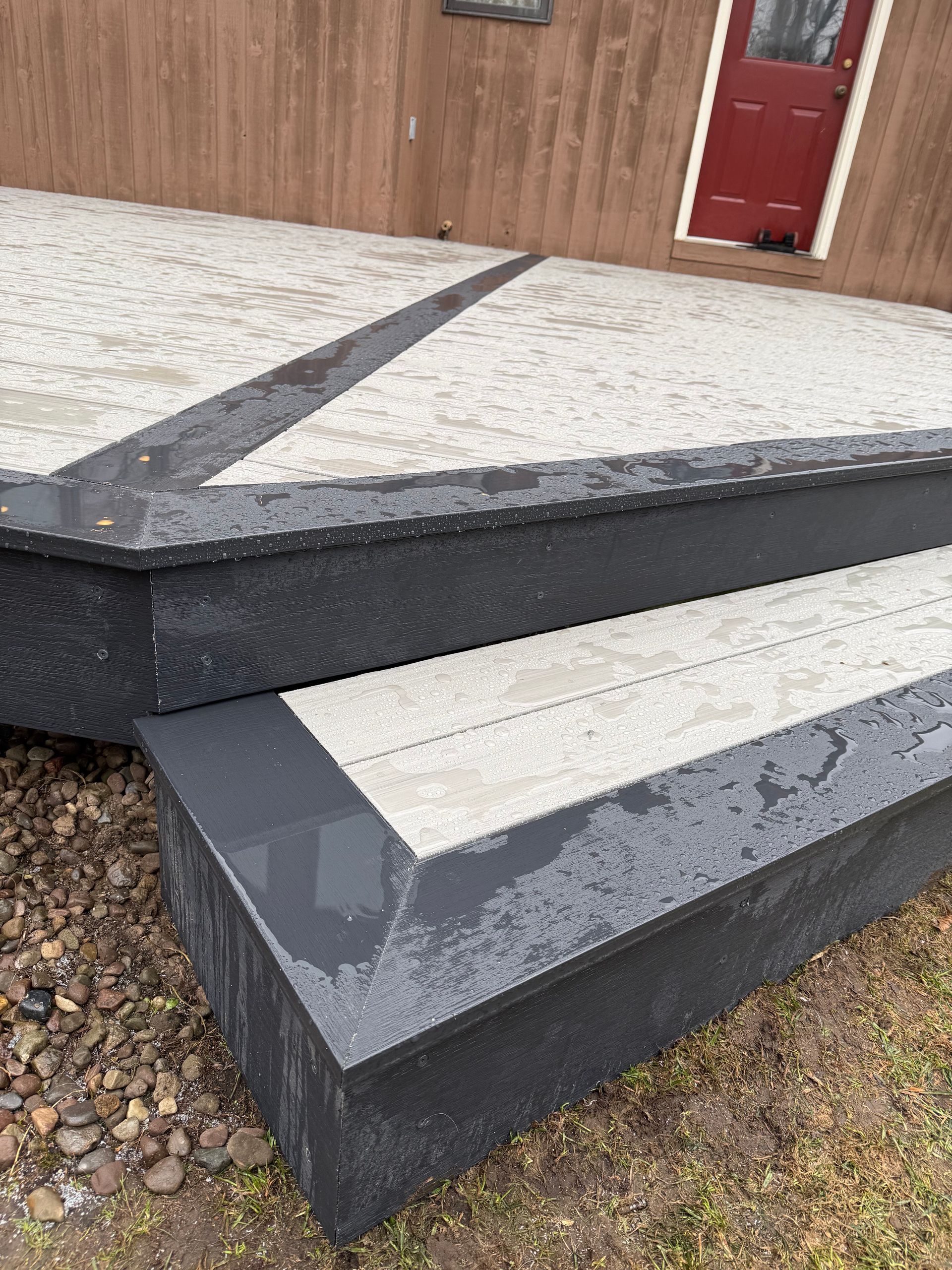 Tiered concrete steps with dark trim leading to a building entrance and red door