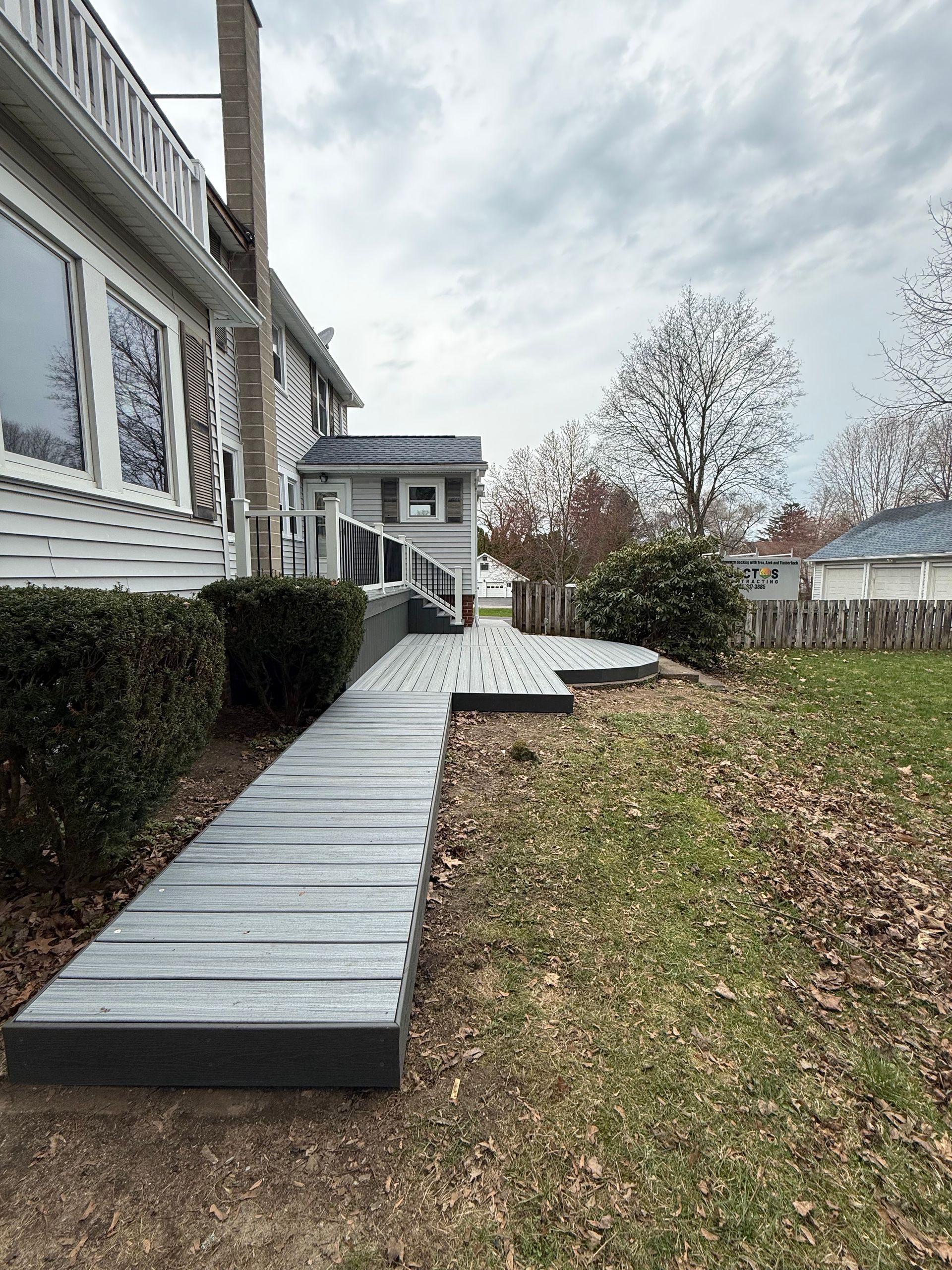 Wooden accessibility ramp beside a house, leading from the porch down to a grassy yard.