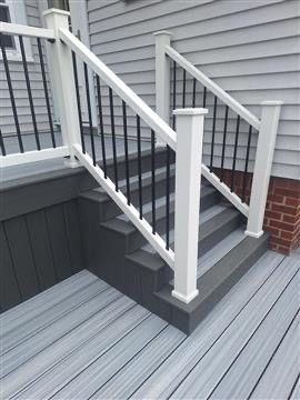 White-railed staircase and deck with gray vinyl flooring beside gray house siding