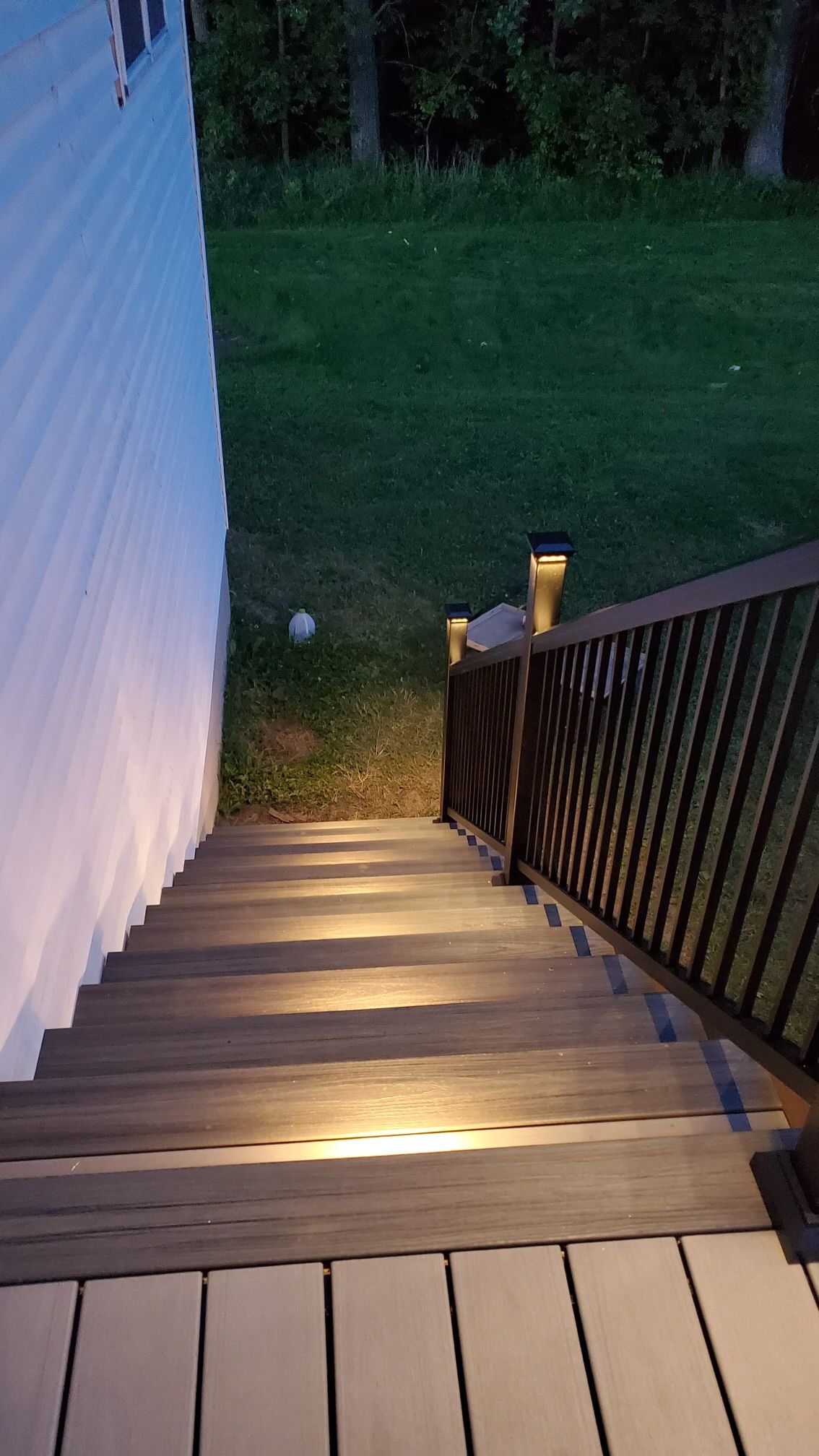 Stairs with built-in lights leading down from a deck. The lights illuminate the steps.