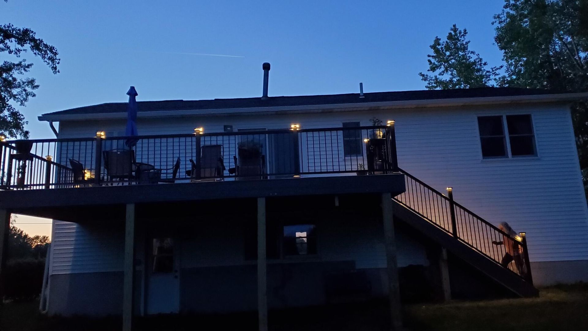 Back of a house at dusk, lit deck with string lights.