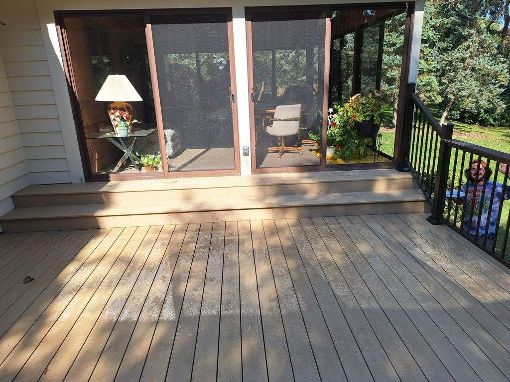 Wooden deck with steps leading to a screened-in porch; a person stands near a railing.