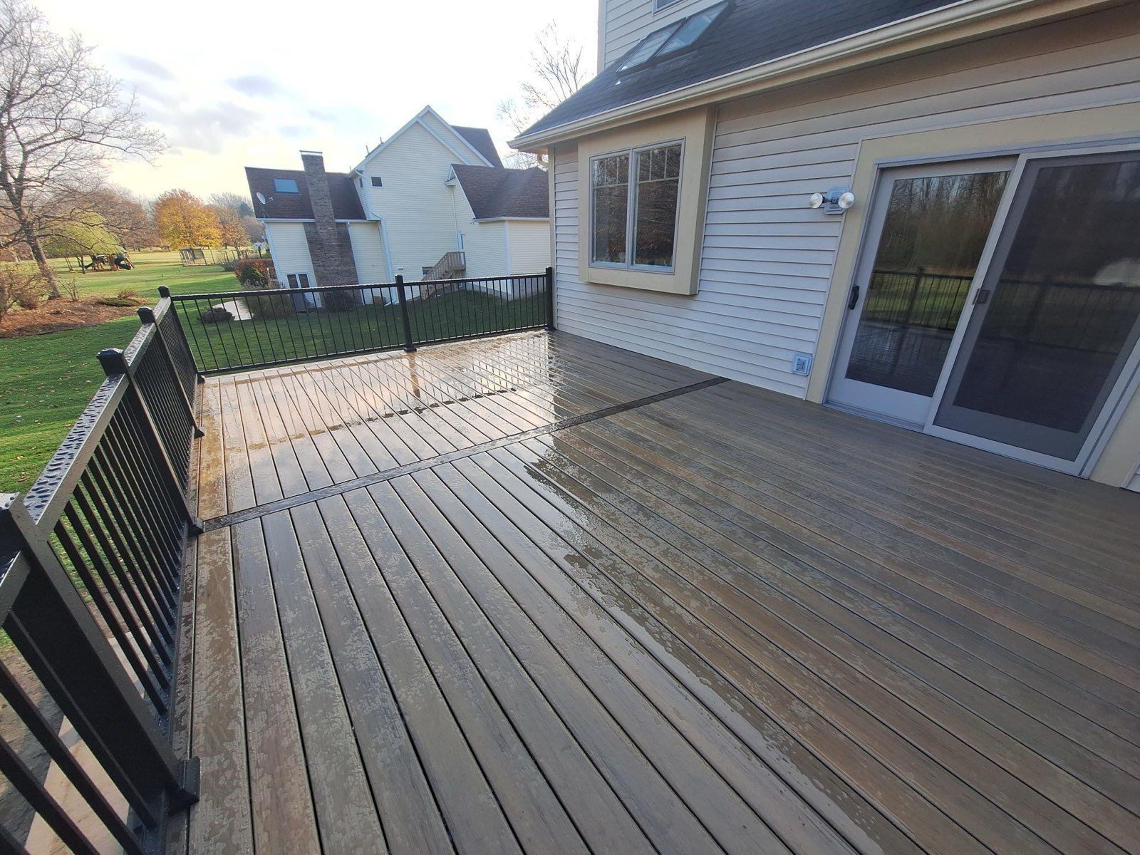 Deck with dark railings and composite boards; house in background.