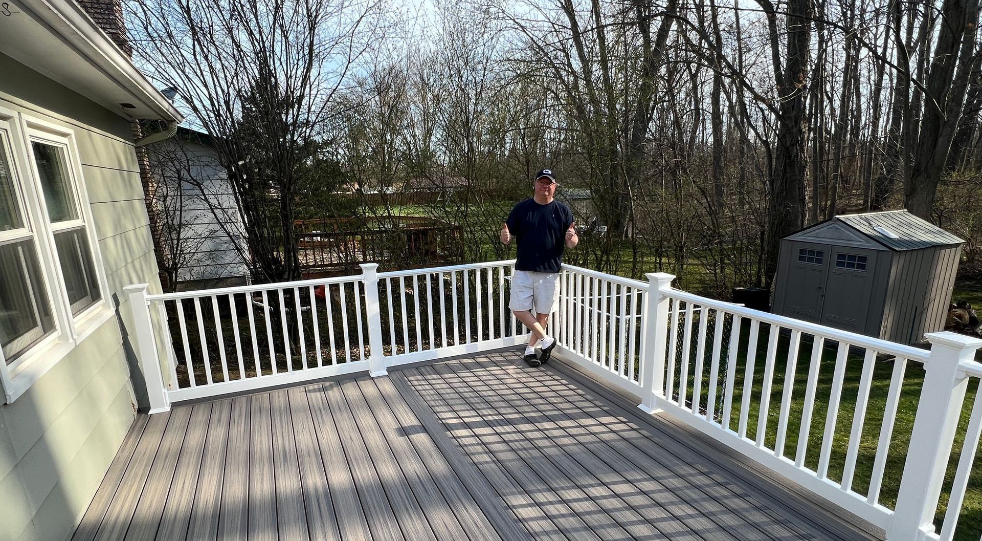 A man is standing on a deck with a white railing.