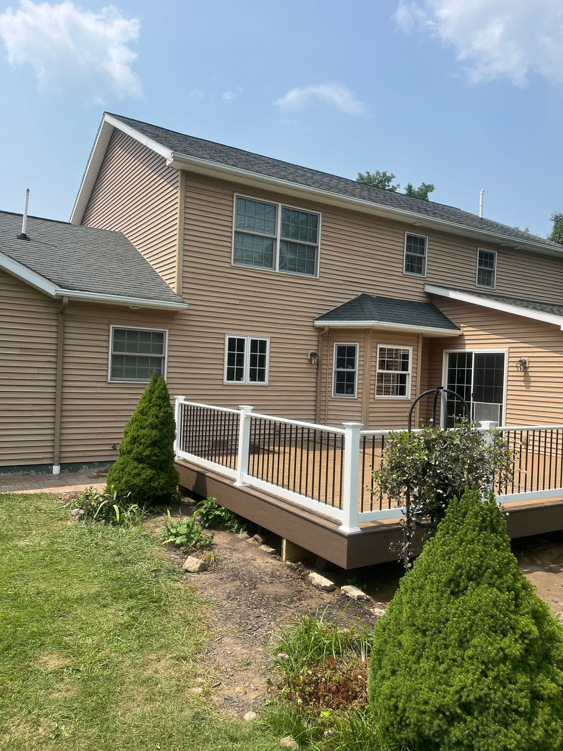 The back of a house with a deck and a white railing.