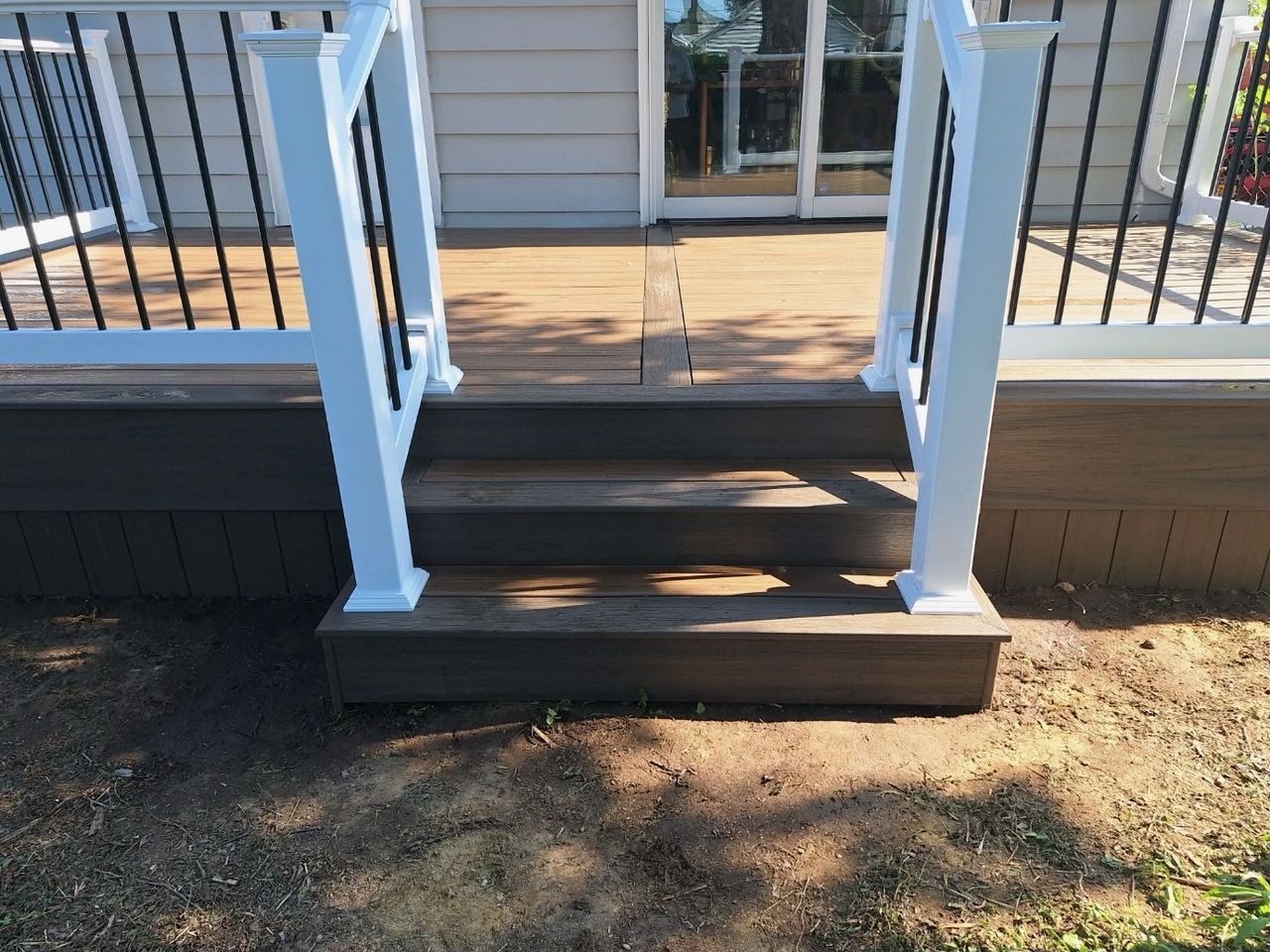 A deck with stairs leading up to it and a white railing.