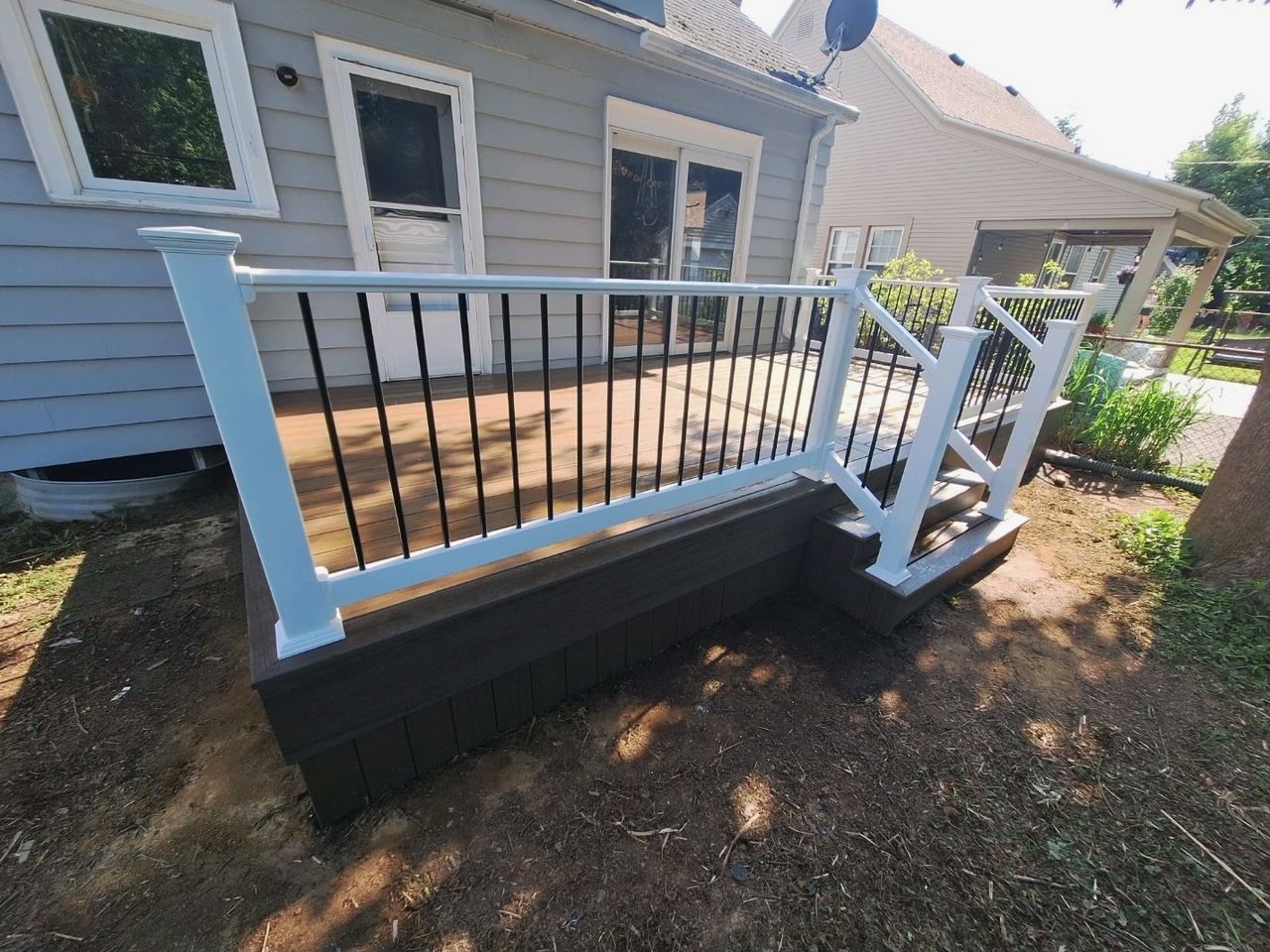 A deck with stairs and a railing is in front of a house.