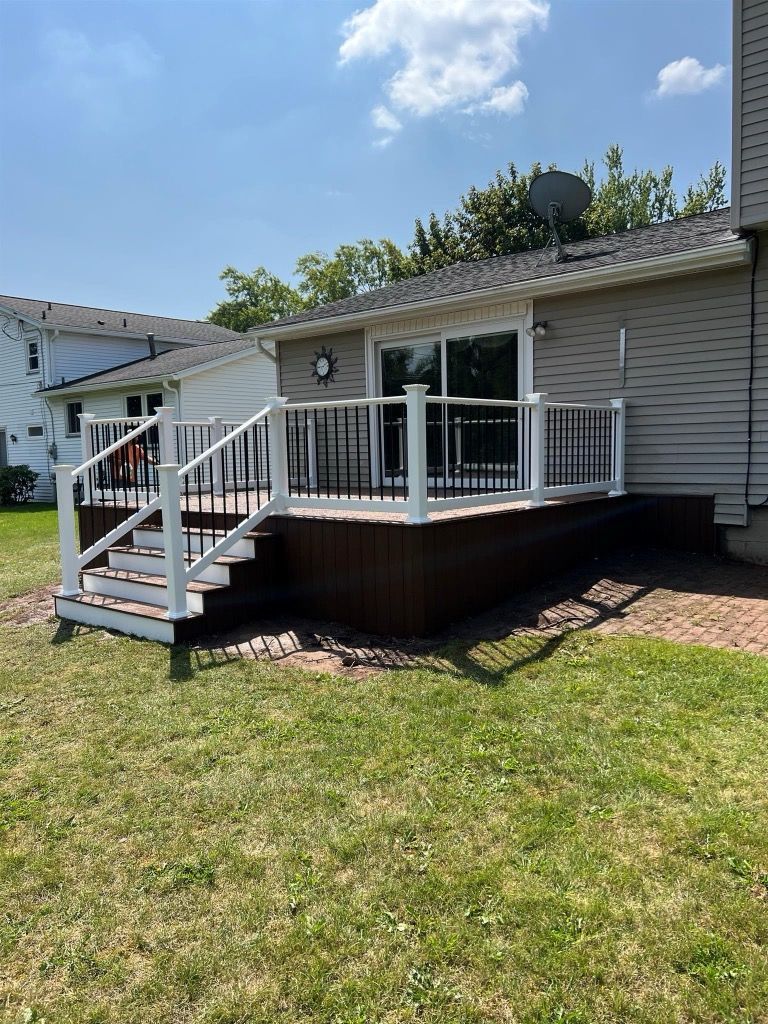 A deck with stairs leading up to it is in the backyard of a house.