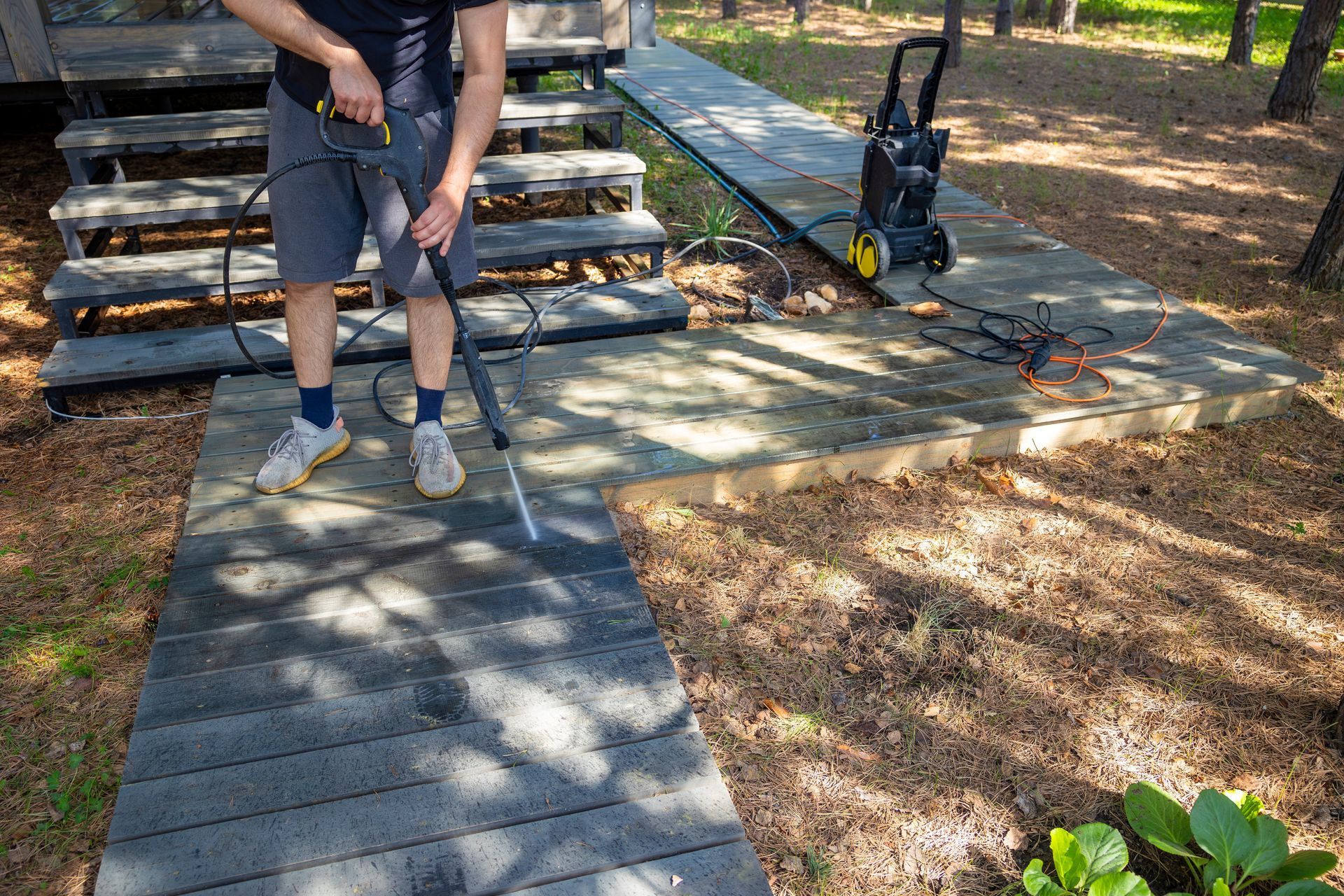 A person stands on a wooden walkway under construction in a wooded park area.