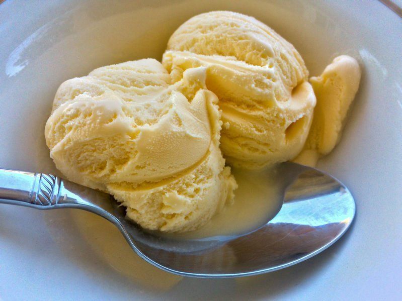 Three scoops of vanilla ice cream in a bowl with a spoon