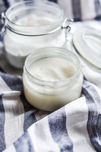 Small glass jars of white yogurt on a blue-and-white striped cloth.