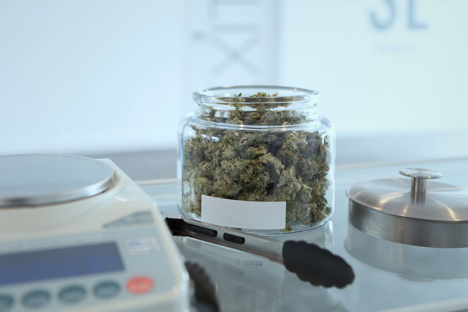 Laboratory scale with a jar of dried cannabis on the counter
