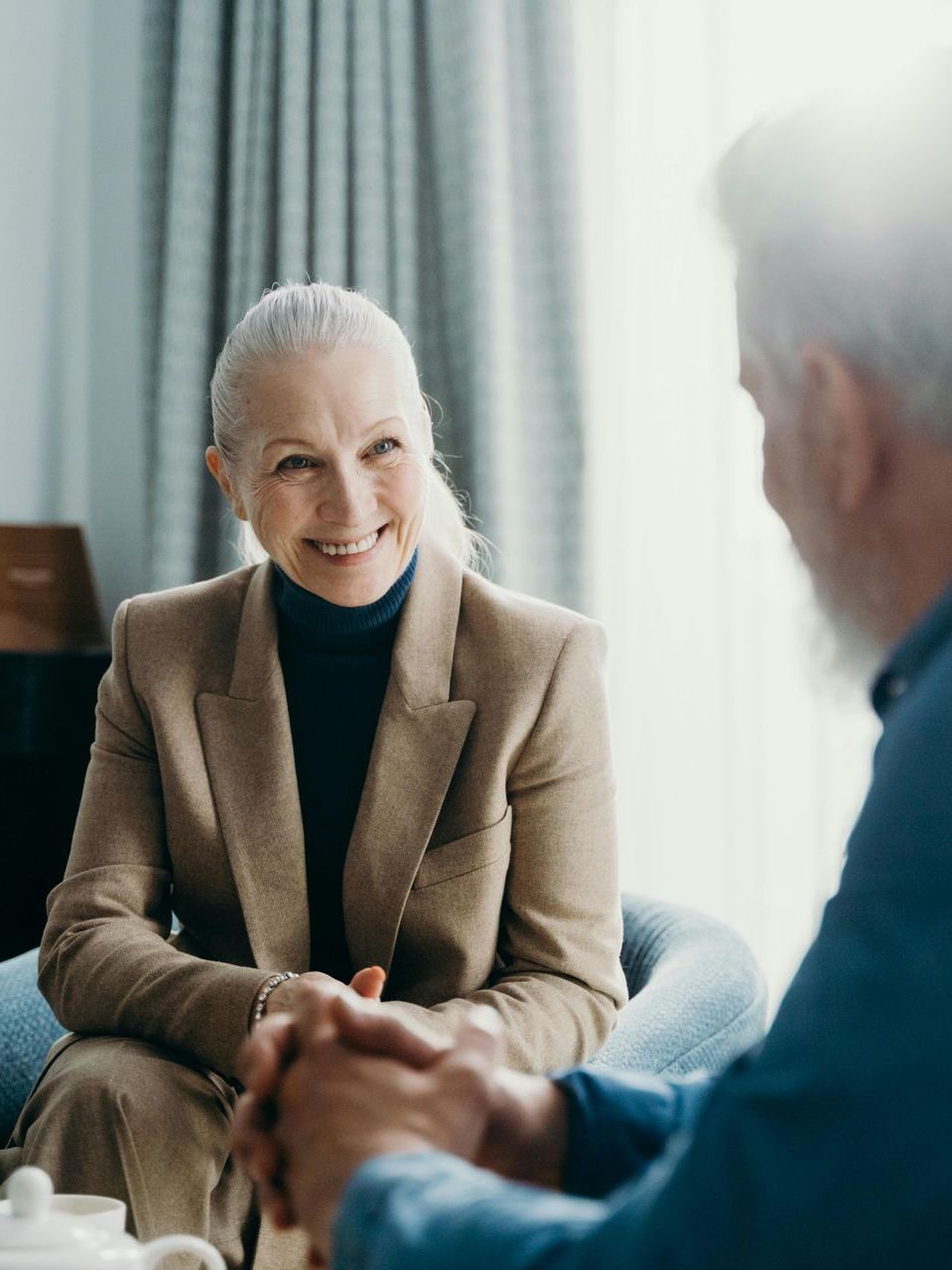 A woman is sitting in a chair talking to a man.