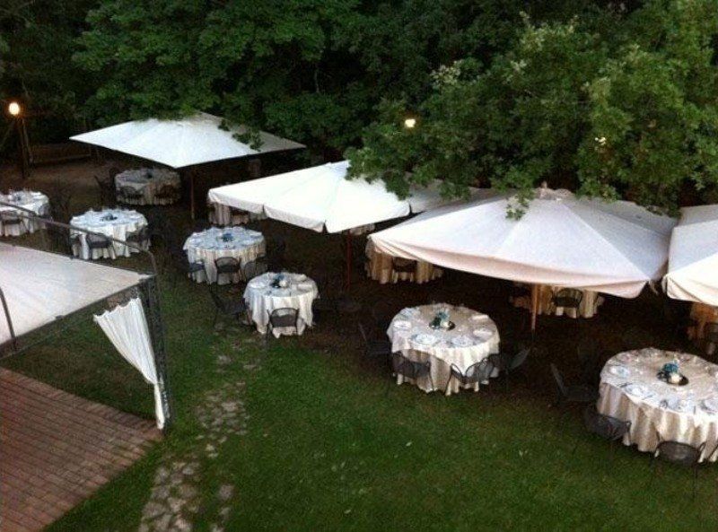 Una fila di tavoli e ombrelloni in una zona erbosa