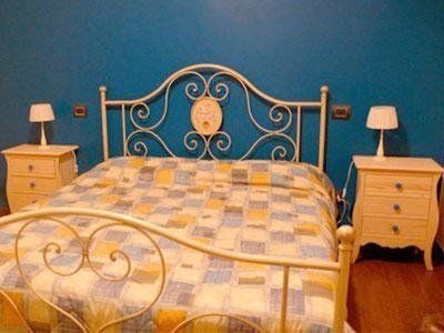 Una camera con un letto, due comodini e due lampade.