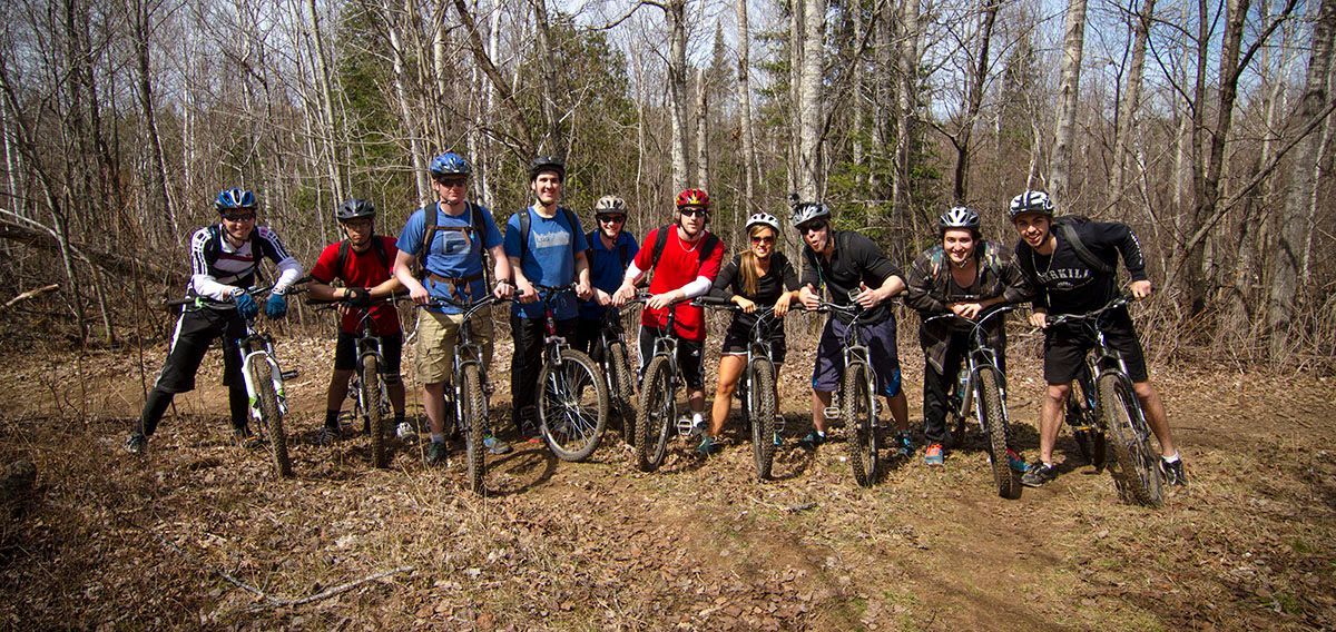 A group of mountain bikers, wearing helmets.