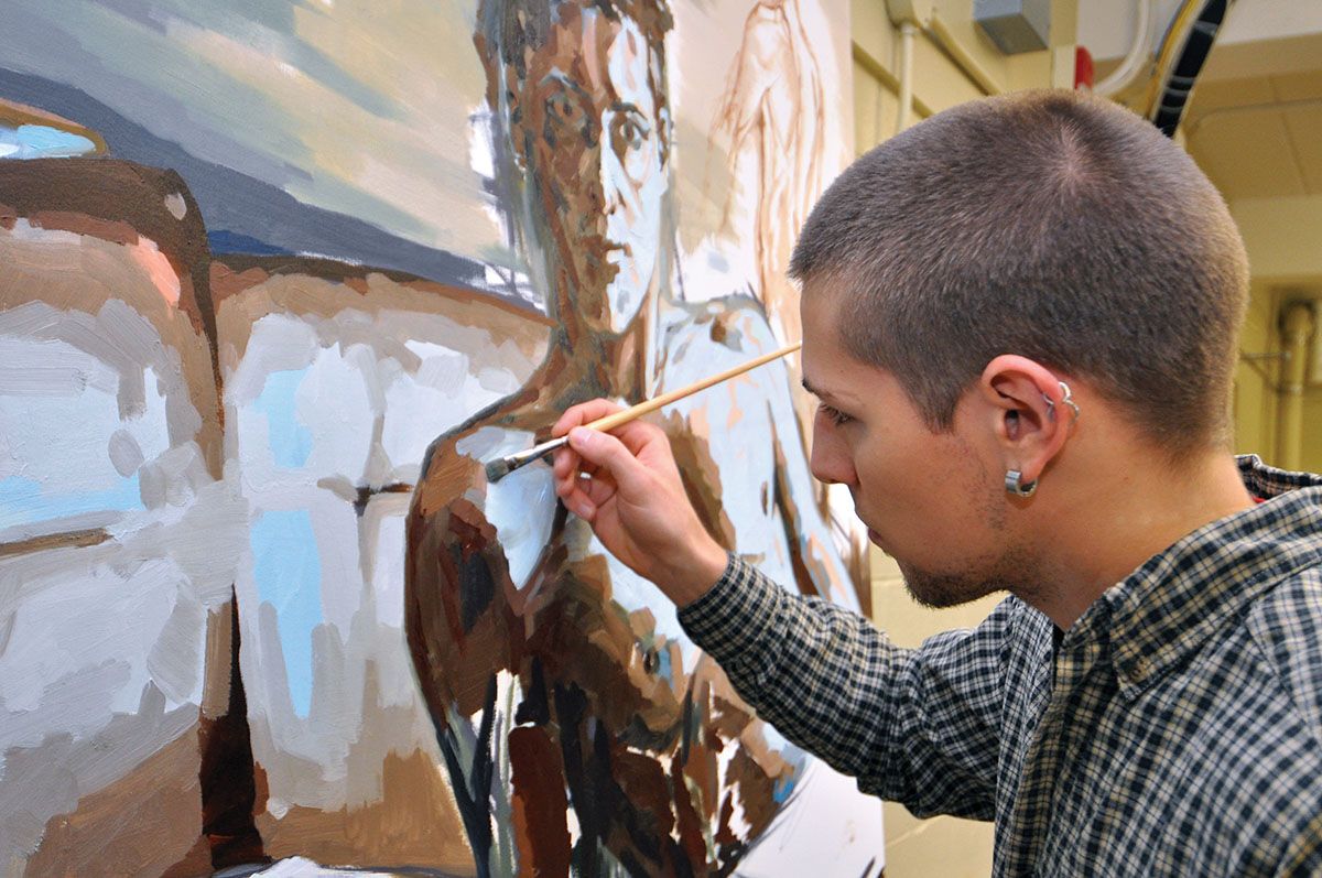 Artist painting a male figure on a large canvas with a brush, using brown and light blue colours.