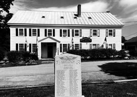Black-and-white photo of a historic building with a memorial plaque in front