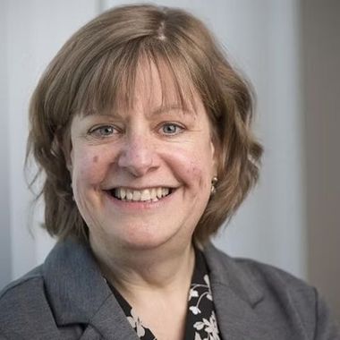 A woman in a suit and floral shirt is smiling for the camera.