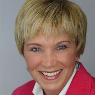 A woman wearing a pink jacket is smiling for the camera.
