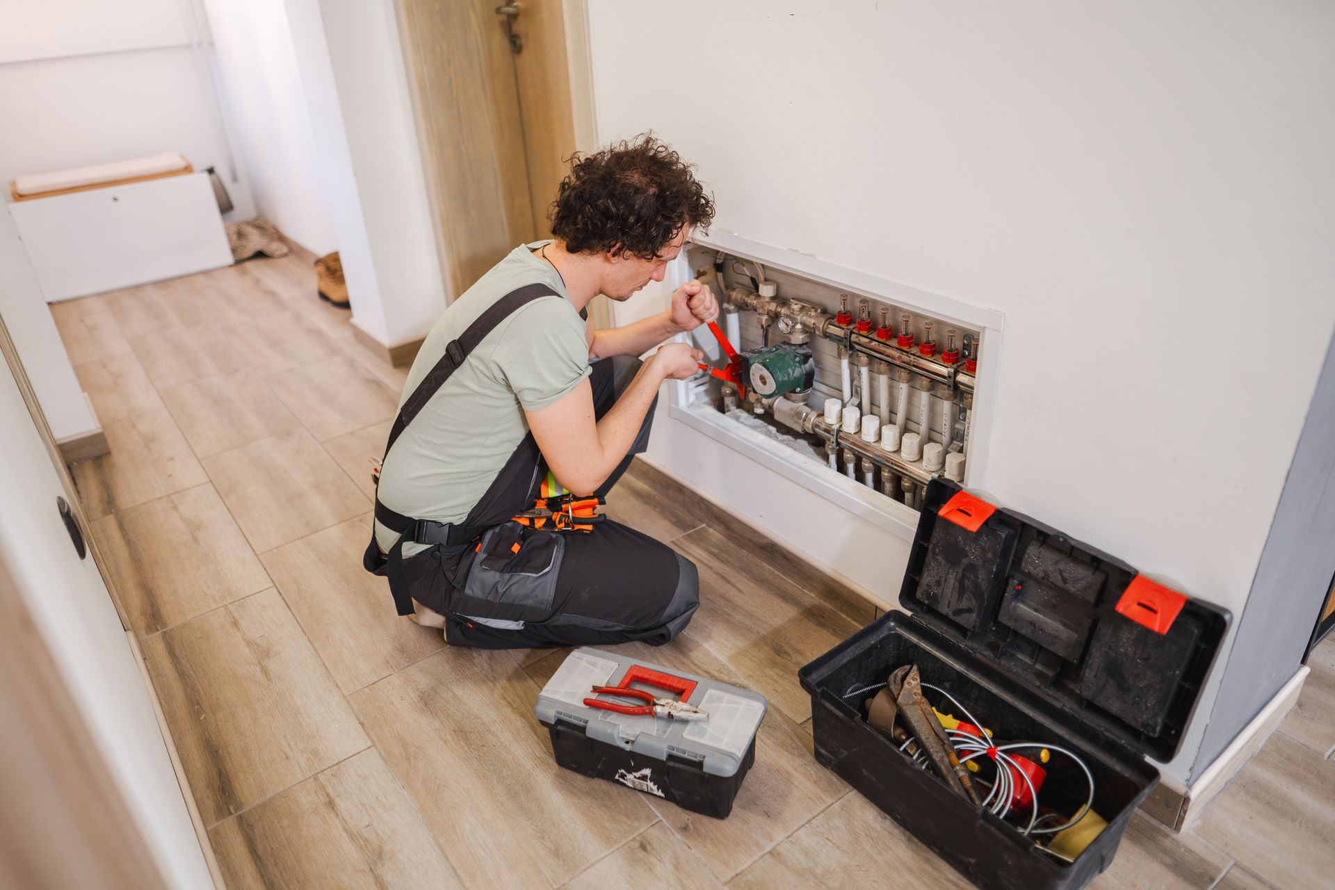An experienced emergency heating contractor fixing a problem with underfloor heating pipes