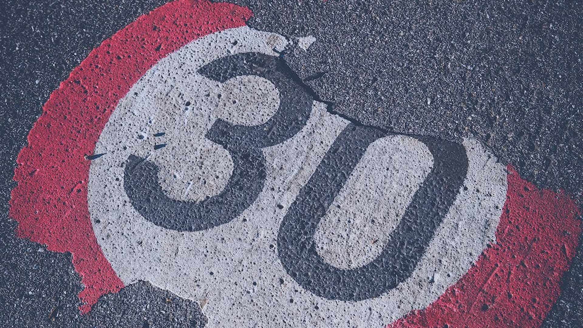 A 30 speed limit sign is painted on the road