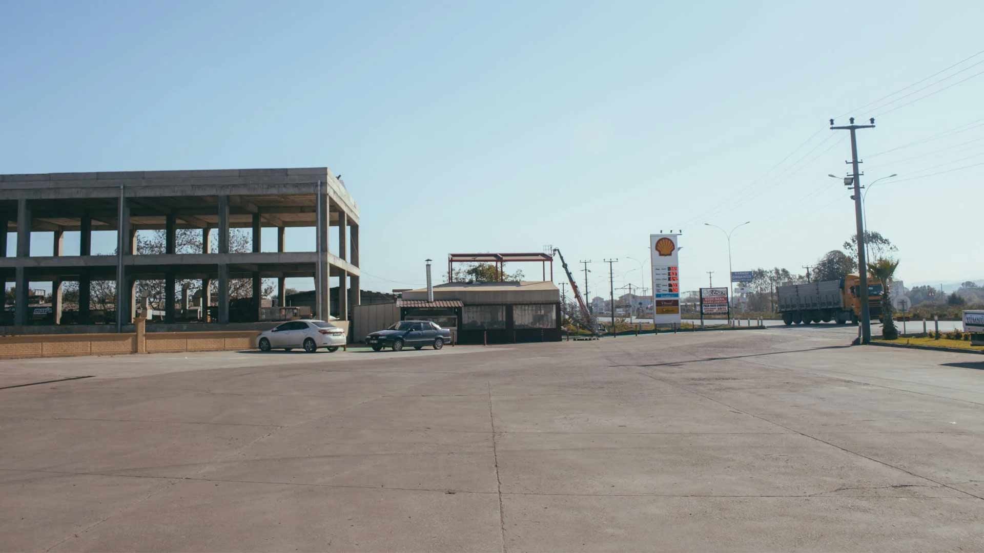 A parking lot with cars parked in front of a building under construction.