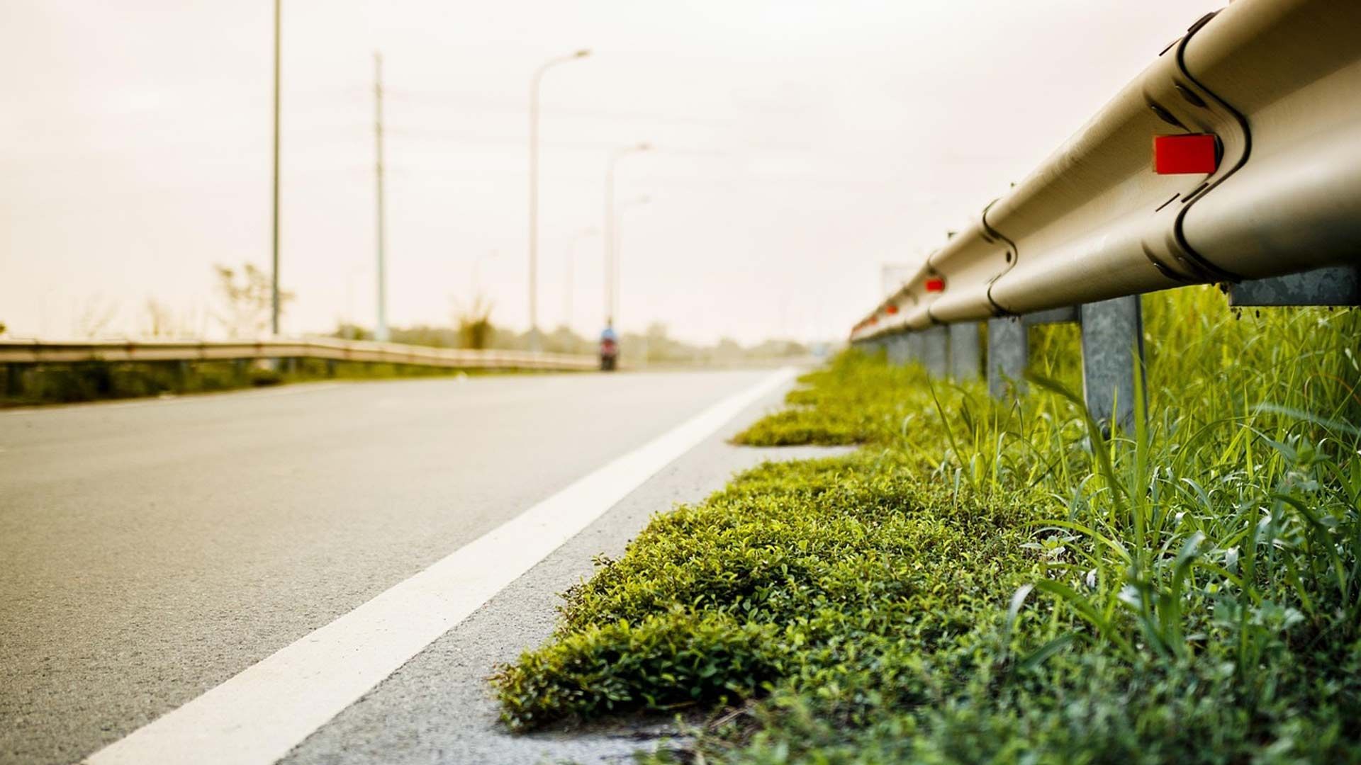 A close up of a highway with grass growing on the side of it.