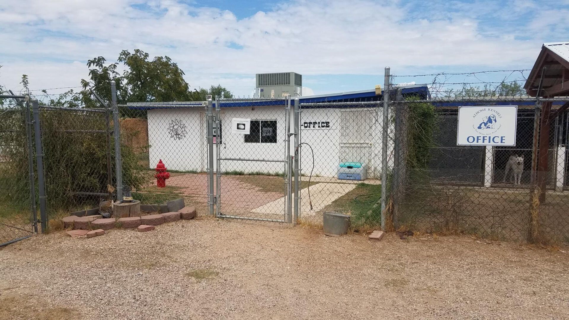 A fenced-in animal shelter office building with a red fire hydrant, clear sky.
