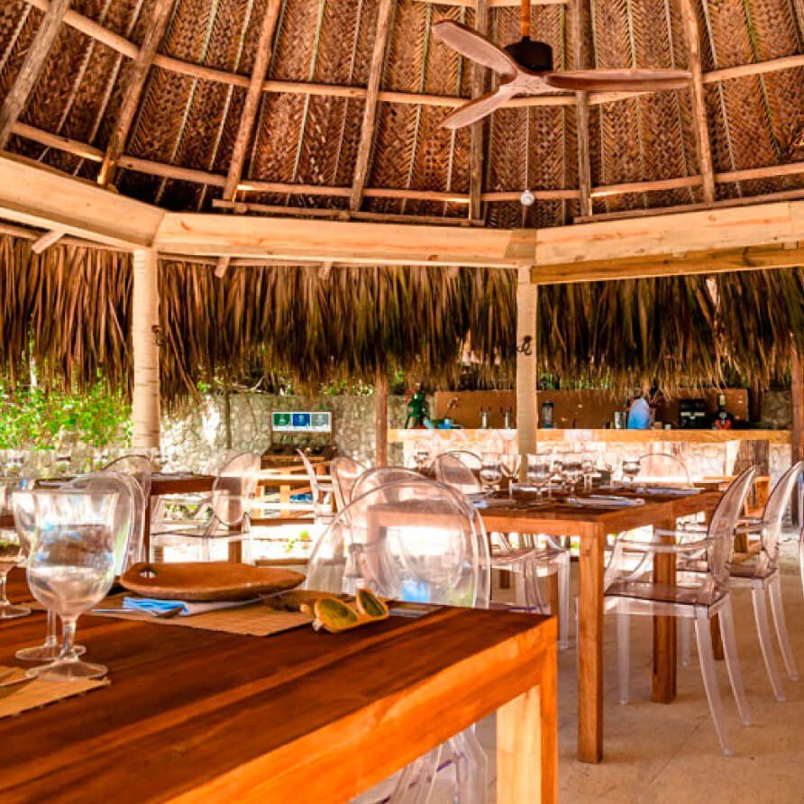 Un restaurante con mesas y sillas bajo un techo de paja
