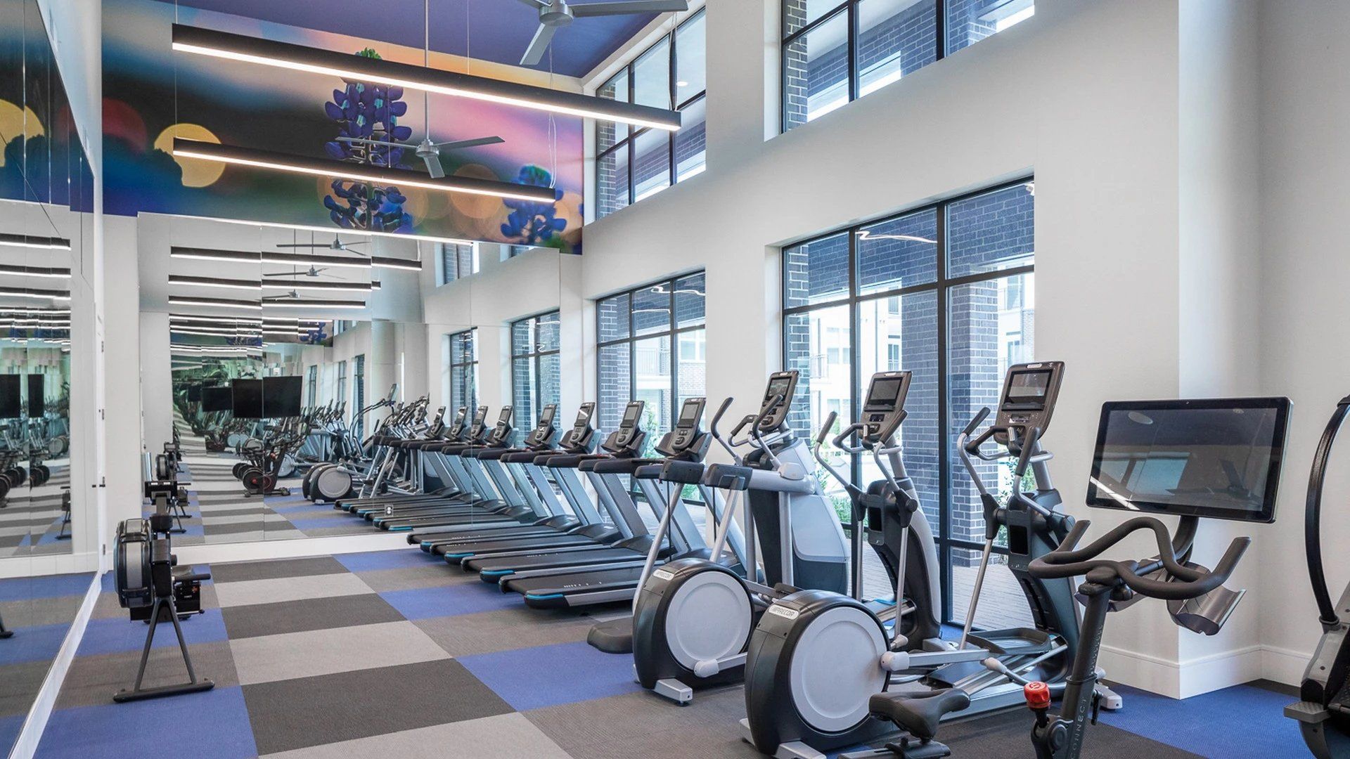 A large gym with a lot of treadmills and exercise bikes.